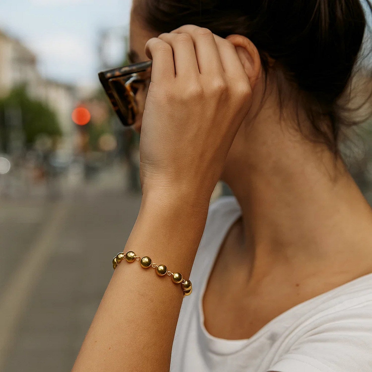 14K yellow gold polished pebble bead bracelet on a woman's wrist.