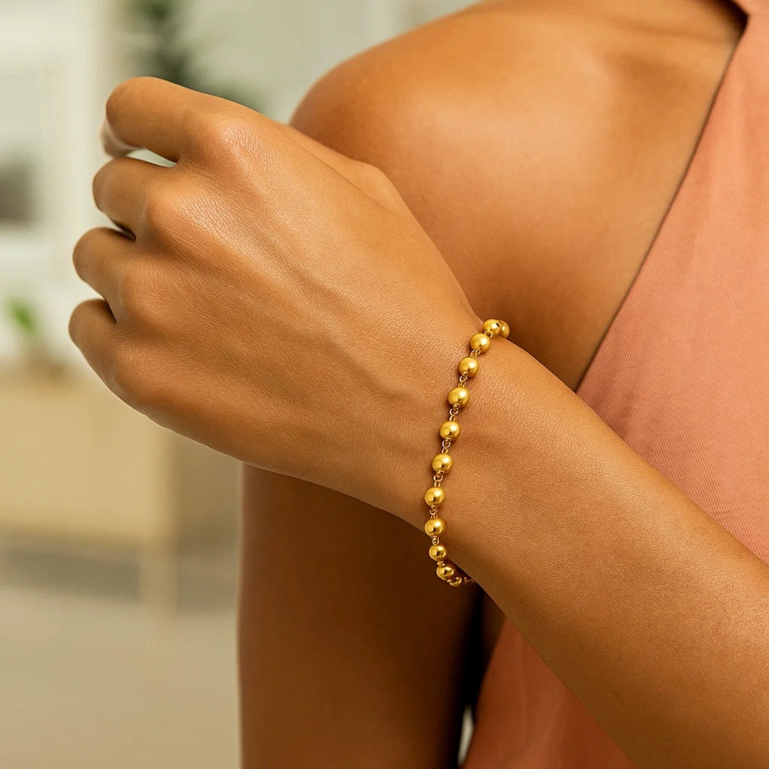 14K yellow gold polished pebble bead bracelet on a person's arm.