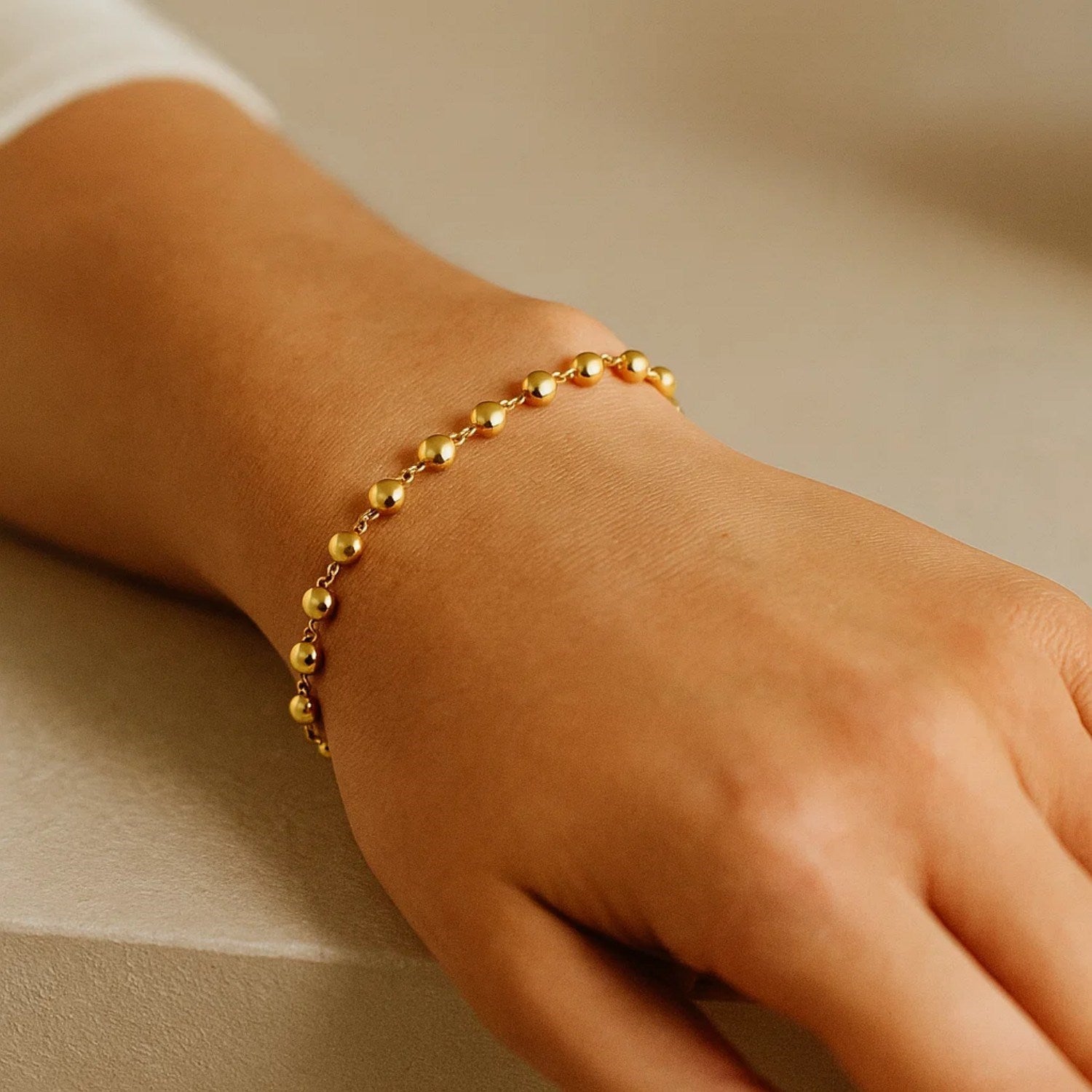 14K yellow gold polished pebble bead bracelet on a person's wrist.