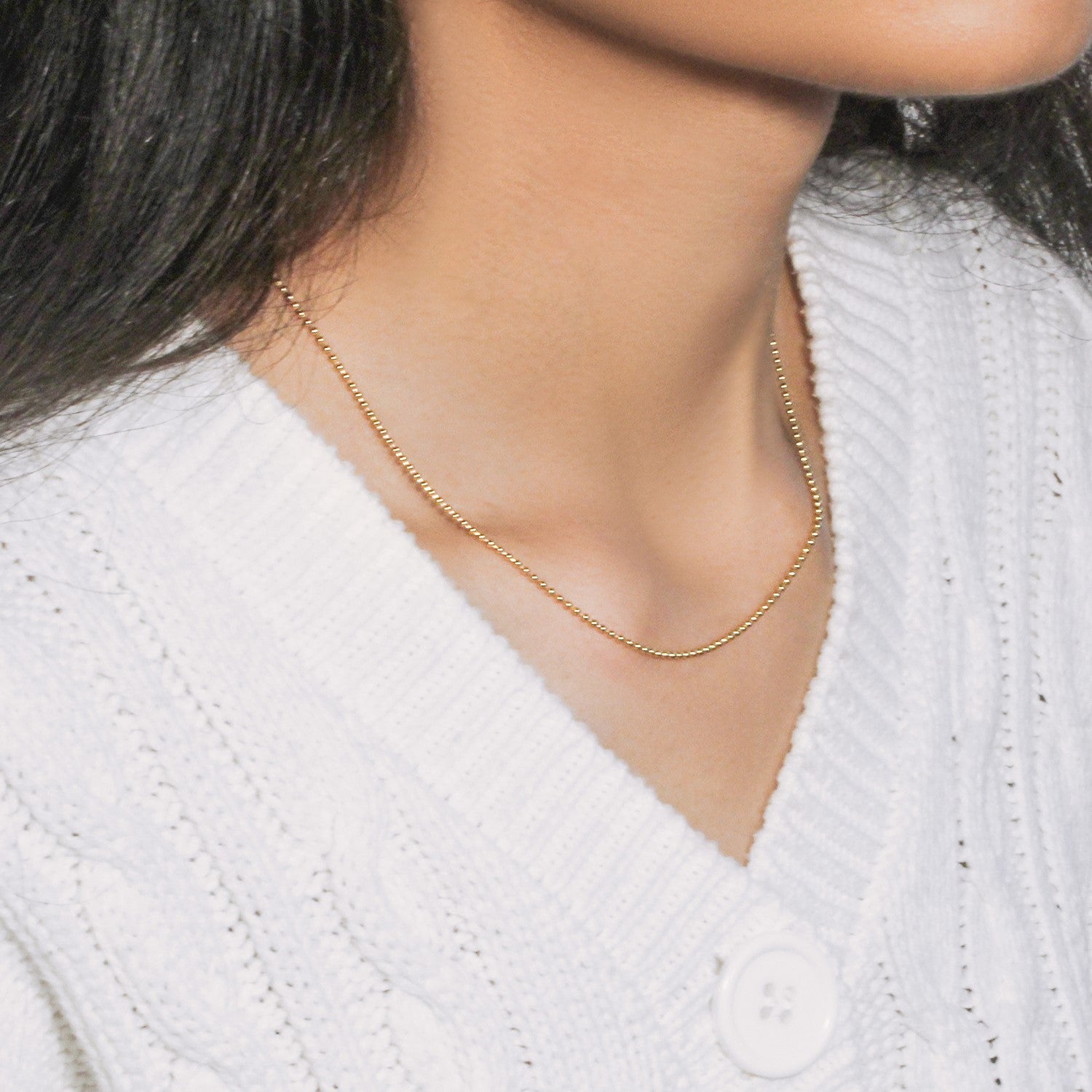 14k yellow gold 1.5mm bead chain on a person wearing a white sweater.