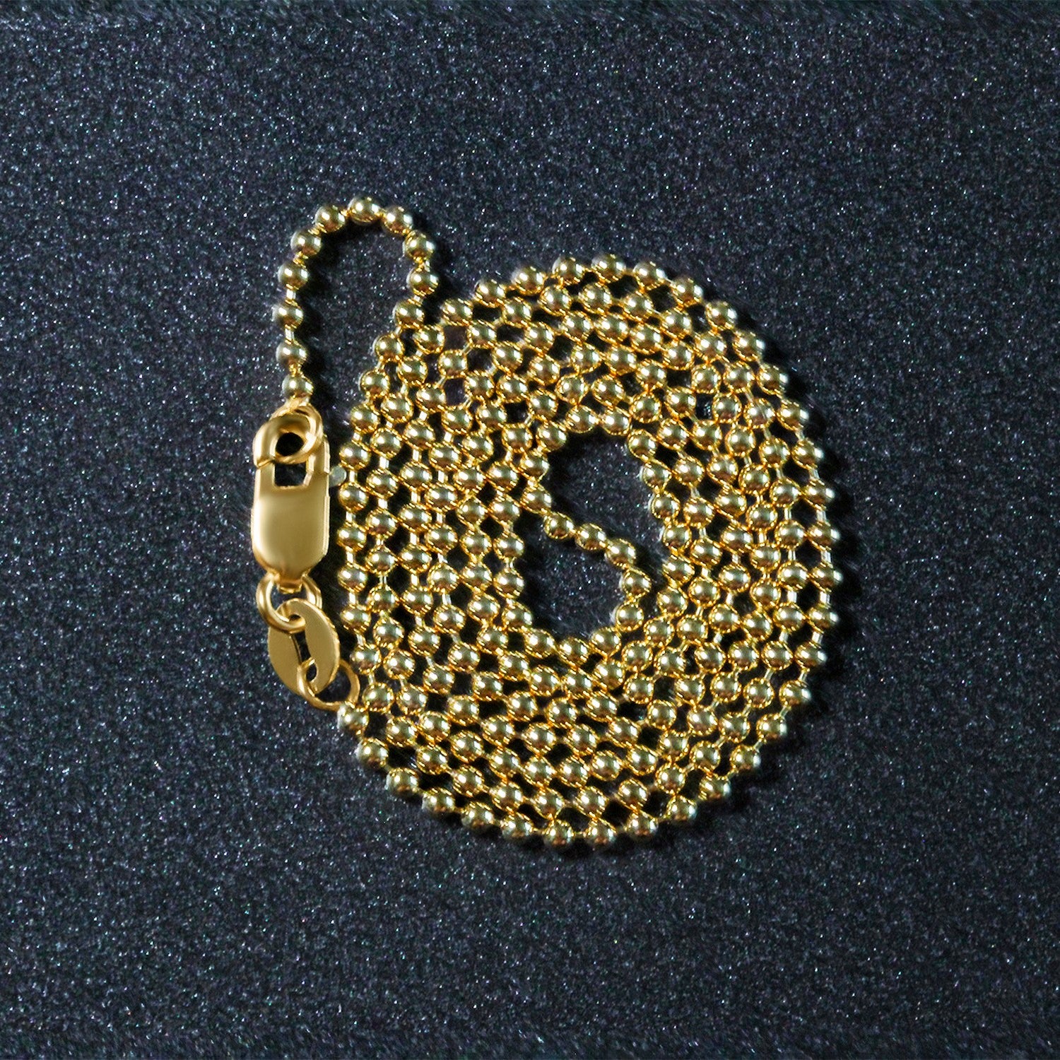 A coiled 14k yellow gold bead chain with a lobster clasp.