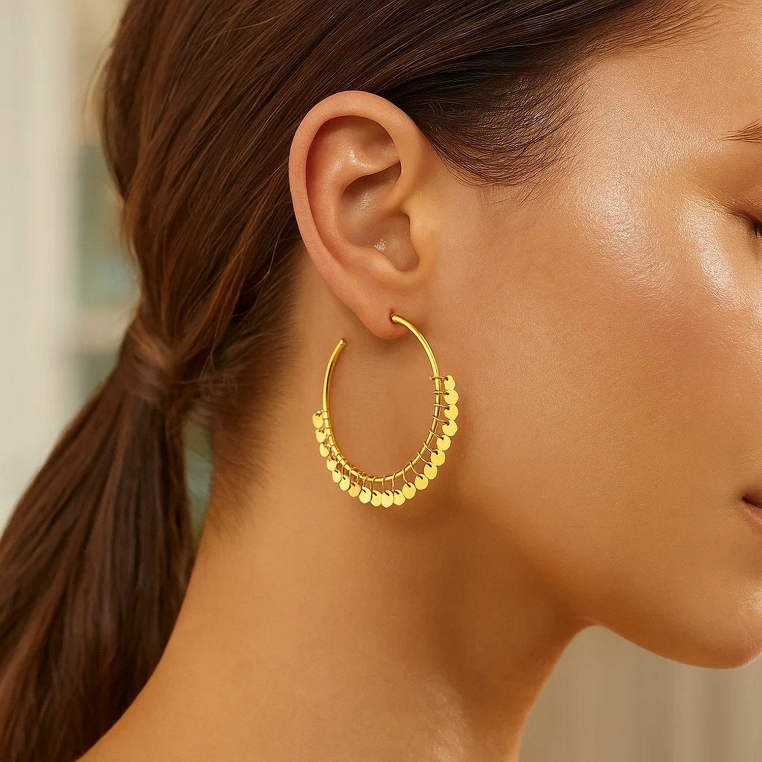14k yellow gold hoop earrings with dangling sequins on a model.
