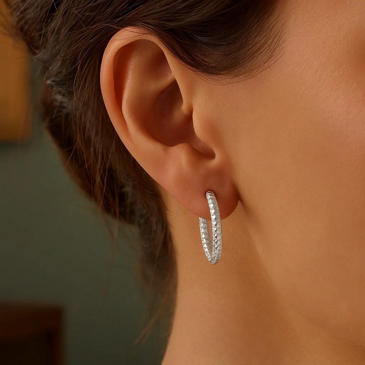 Sterling silver large hoop earring with a braid texture on a person's ear.