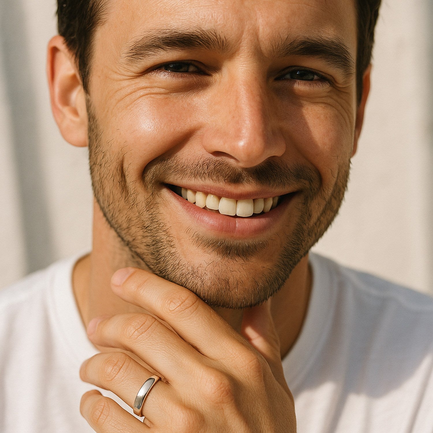 A man smiles, wearing a 14k white gold comfort fit wedding band on his left ring finger.