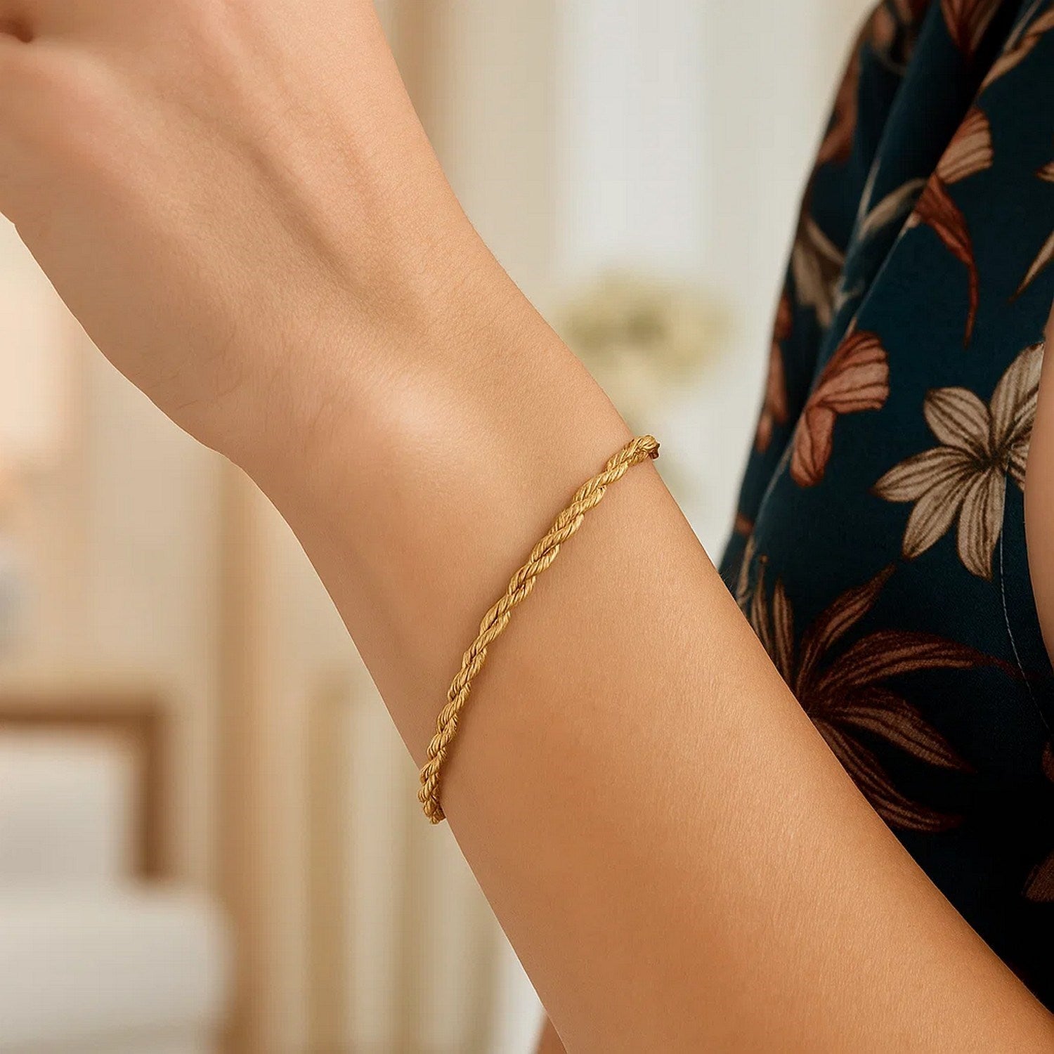 A 14k yellow gold silk rope chain bracelet on a person's arm.