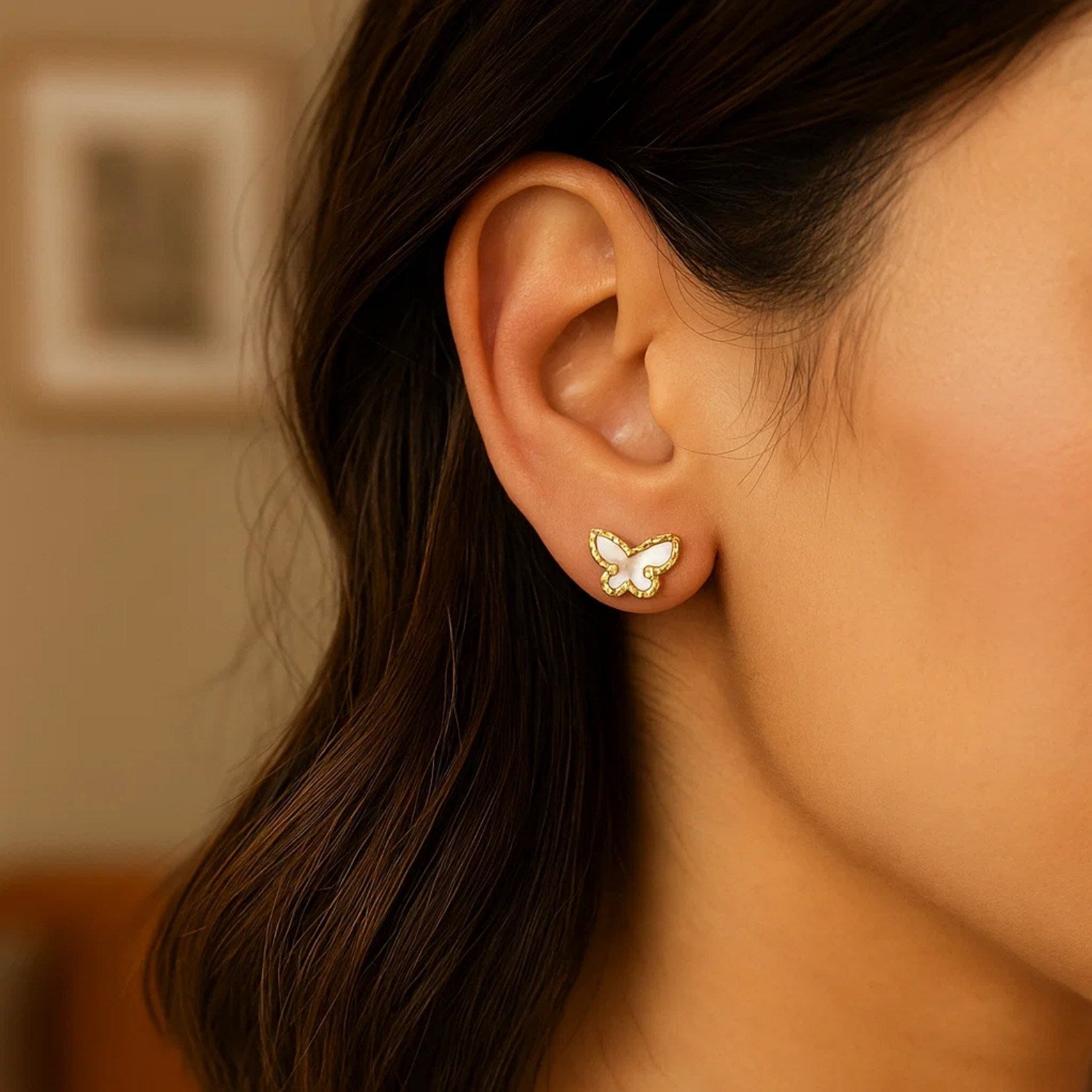 14K yellow gold mother of pearl butterfly stud earring on a woman's ear.