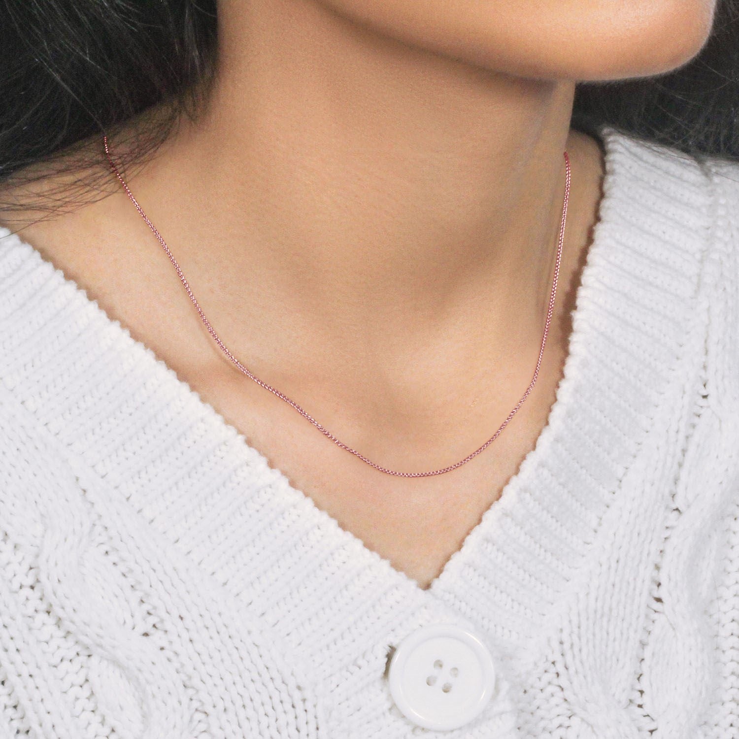A 14k rose gold round wheat chain with a lobster clasp on a person's neck.