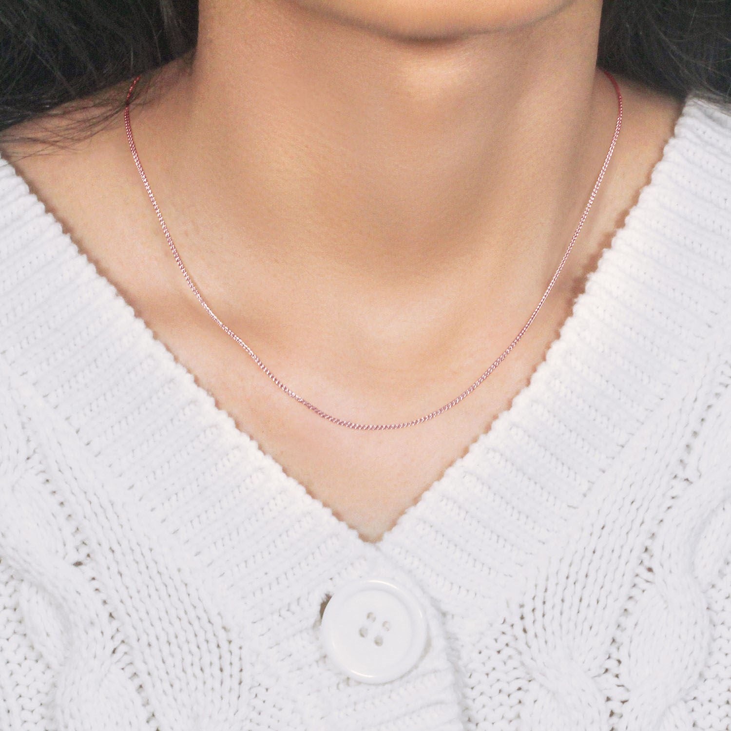 14k rose gold round wheat chain on a person wearing a white cable-knit sweater.