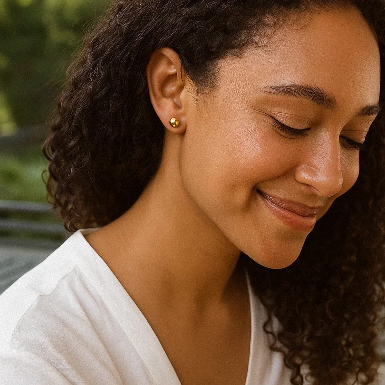 14k yellow gold round motif stud earrings on a woman's ear.