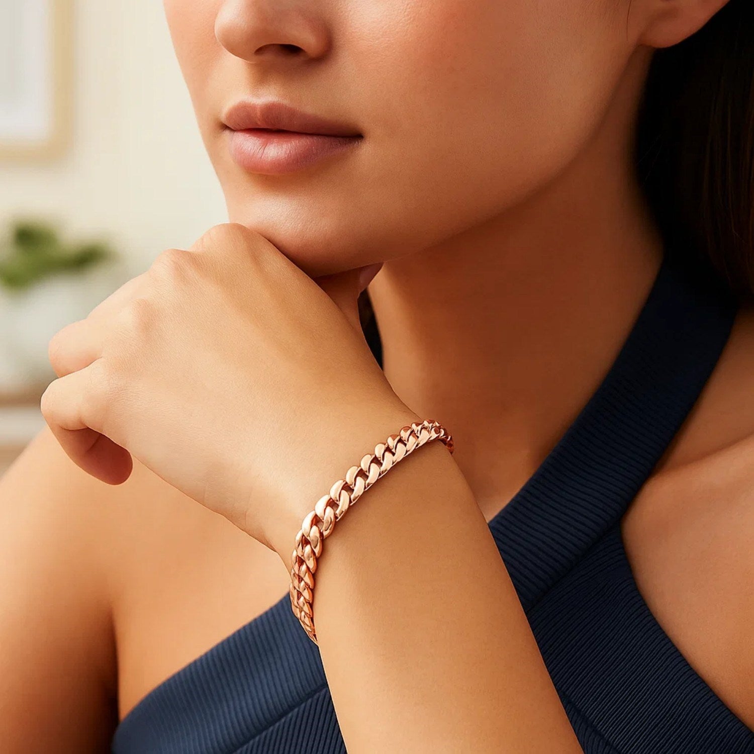A woman wears a 14K rose gold Cuban link bracelet on her wrist.