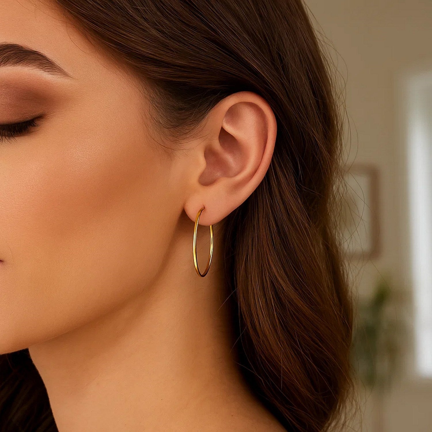 10k yellow gold polished hoop earrings on a woman's ear.