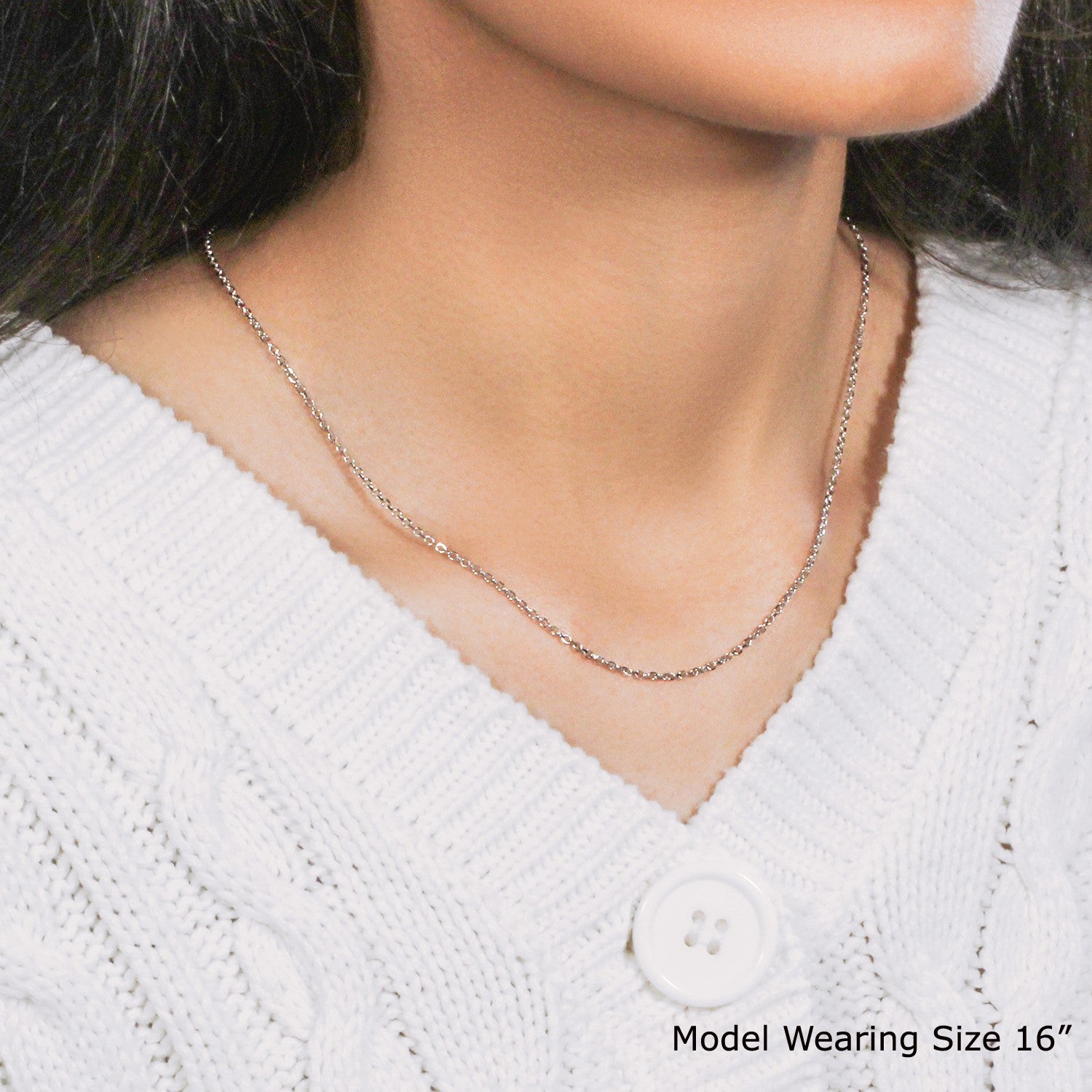 An 18k white gold diamond cut cable link chain is worn around a model's neck.