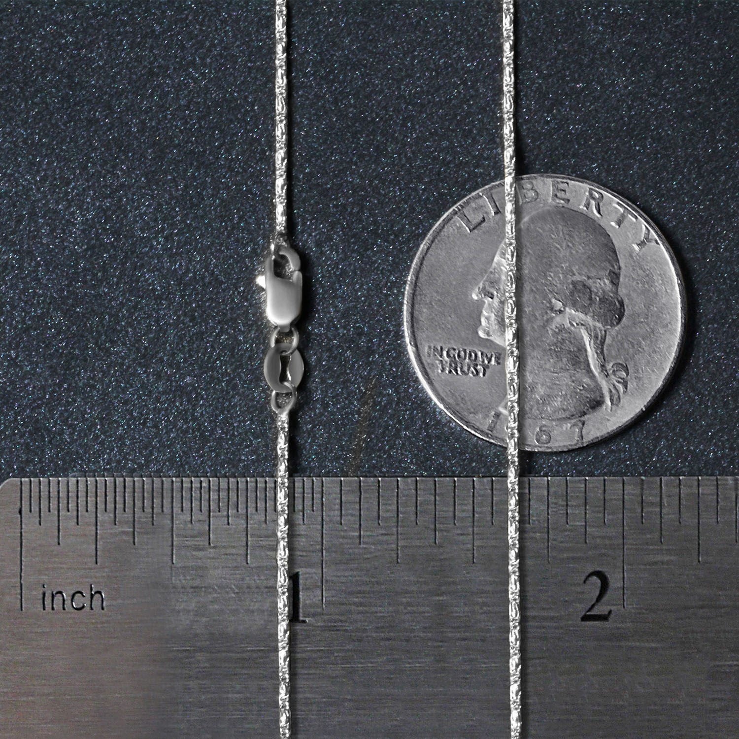 A 14k white gold lumina pendant chain with a lobster clasp is shown next to a ruler and a quarter for scale.