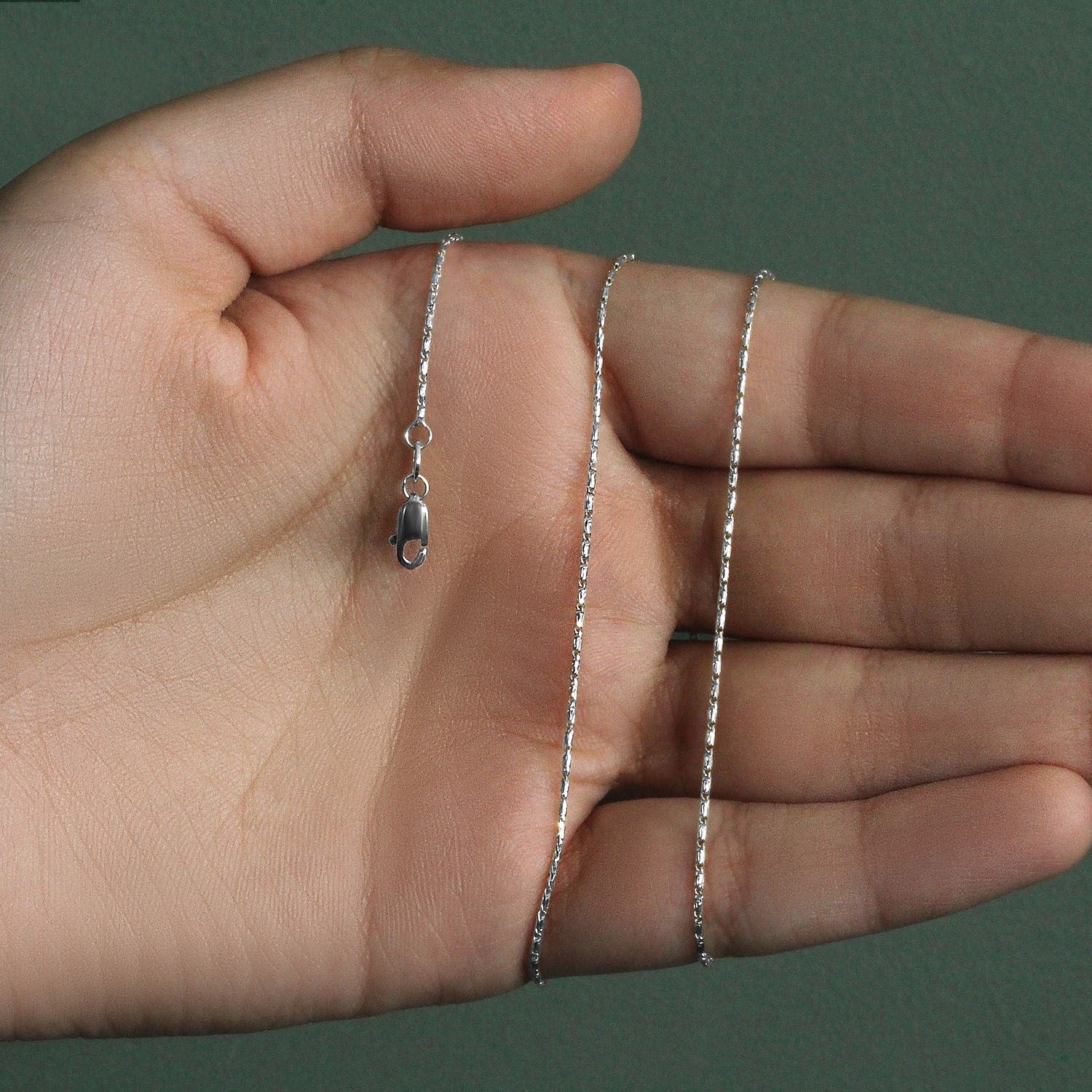 14k white gold lumina pendant chain with a lobster clasp held in an open palm.