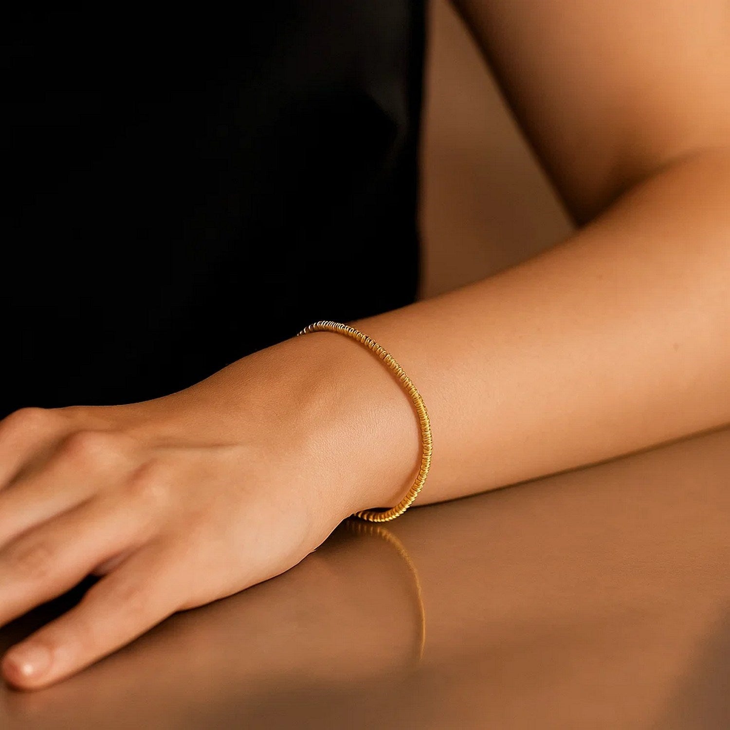14K yellow gold sparkle spring chain bracelet on a person's wrist.