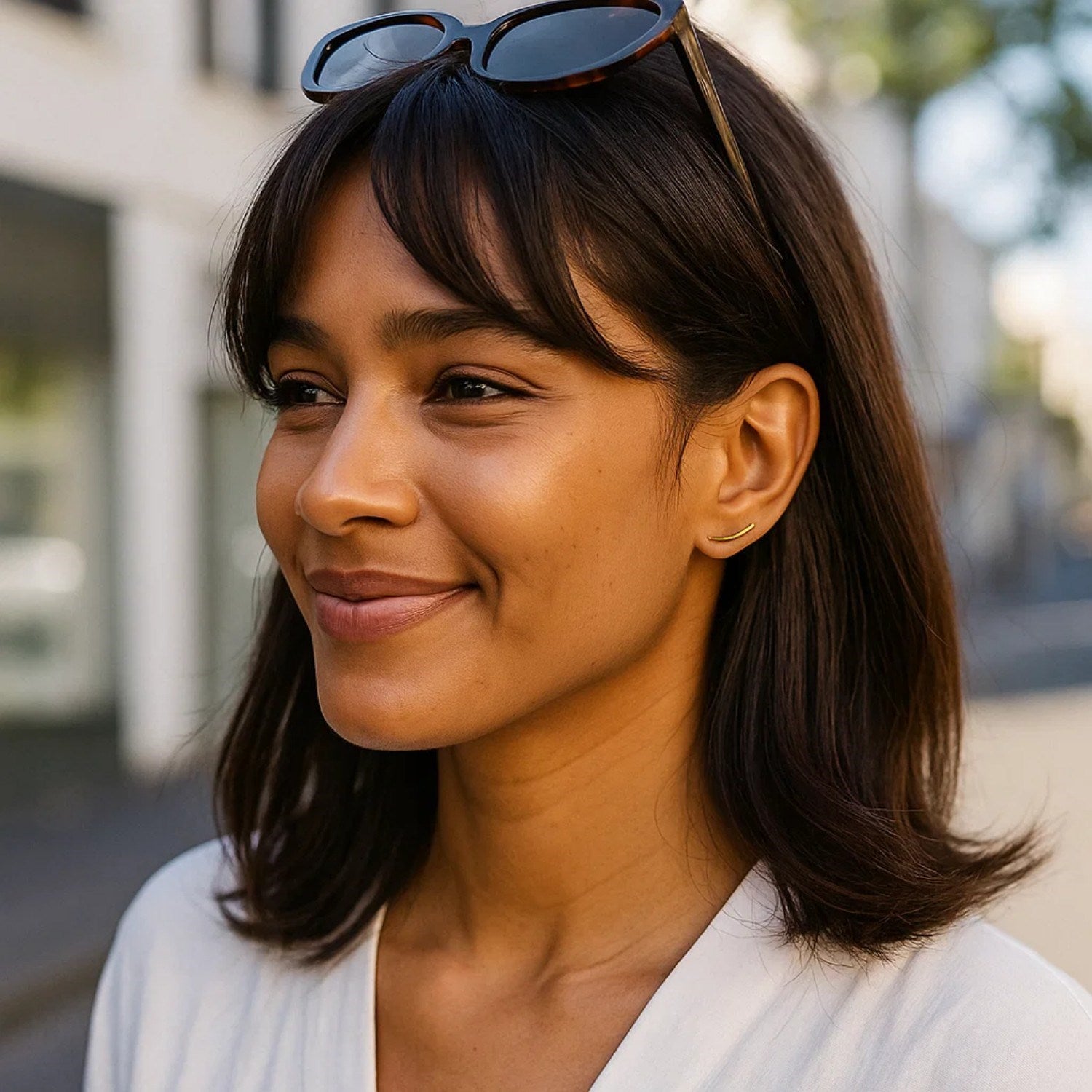 A woman wears a single 14k yellow gold curve climber post earring.