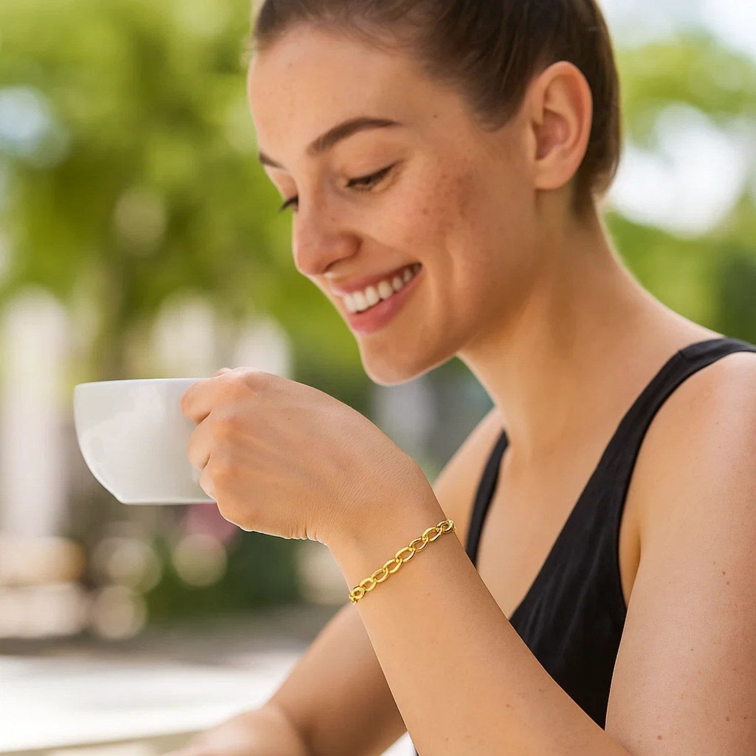 14k yellow gold cable chain bracelet on a woman's wrist as she sips coffee.