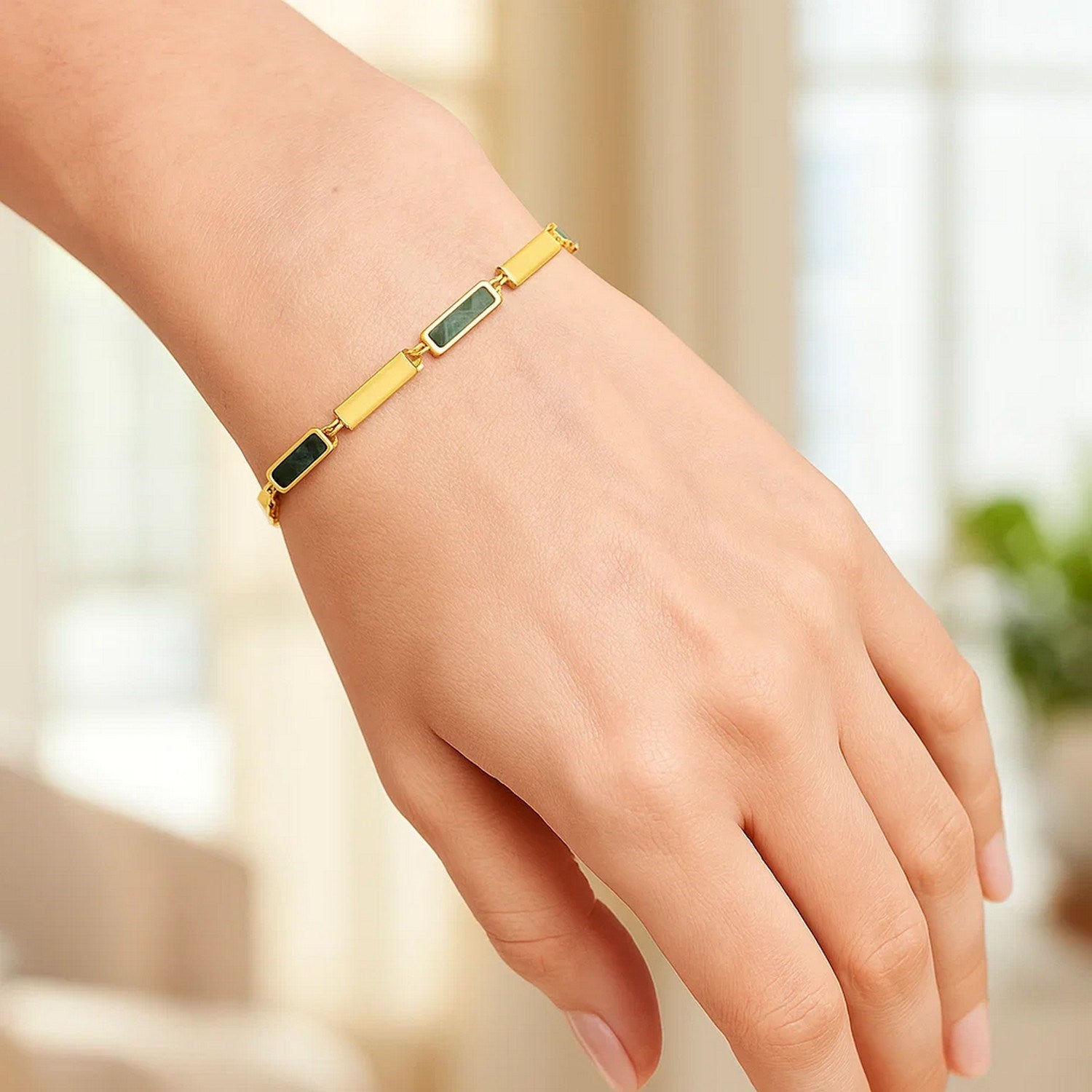 14K yellow gold bracelet with rectangular links, some inlaid with green malachite, on a hand.