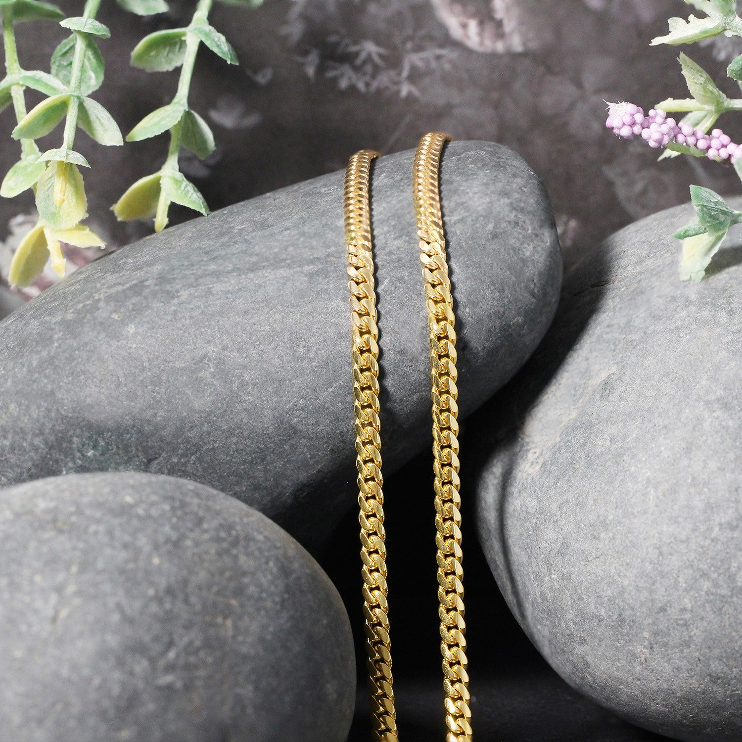 10k yellow gold classic solid Miami Cuban chain, 3.20 mm, draped over grey stones.