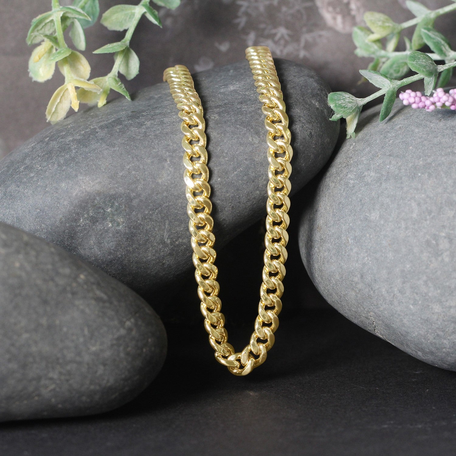 14k yellow gold semi-solid Miami Cuban chain, 5.00 mm wide, resting on dark stones.