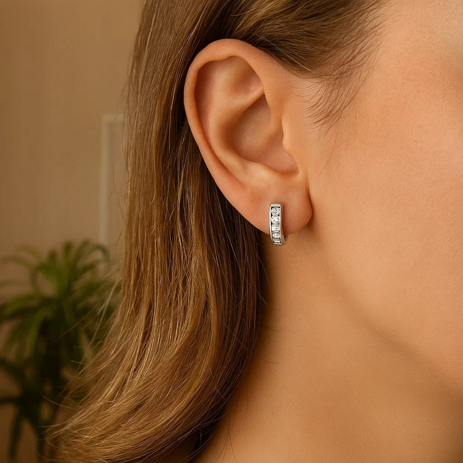 Sterling silver petite hoop earrings with cubic zirconias on a woman's ear.