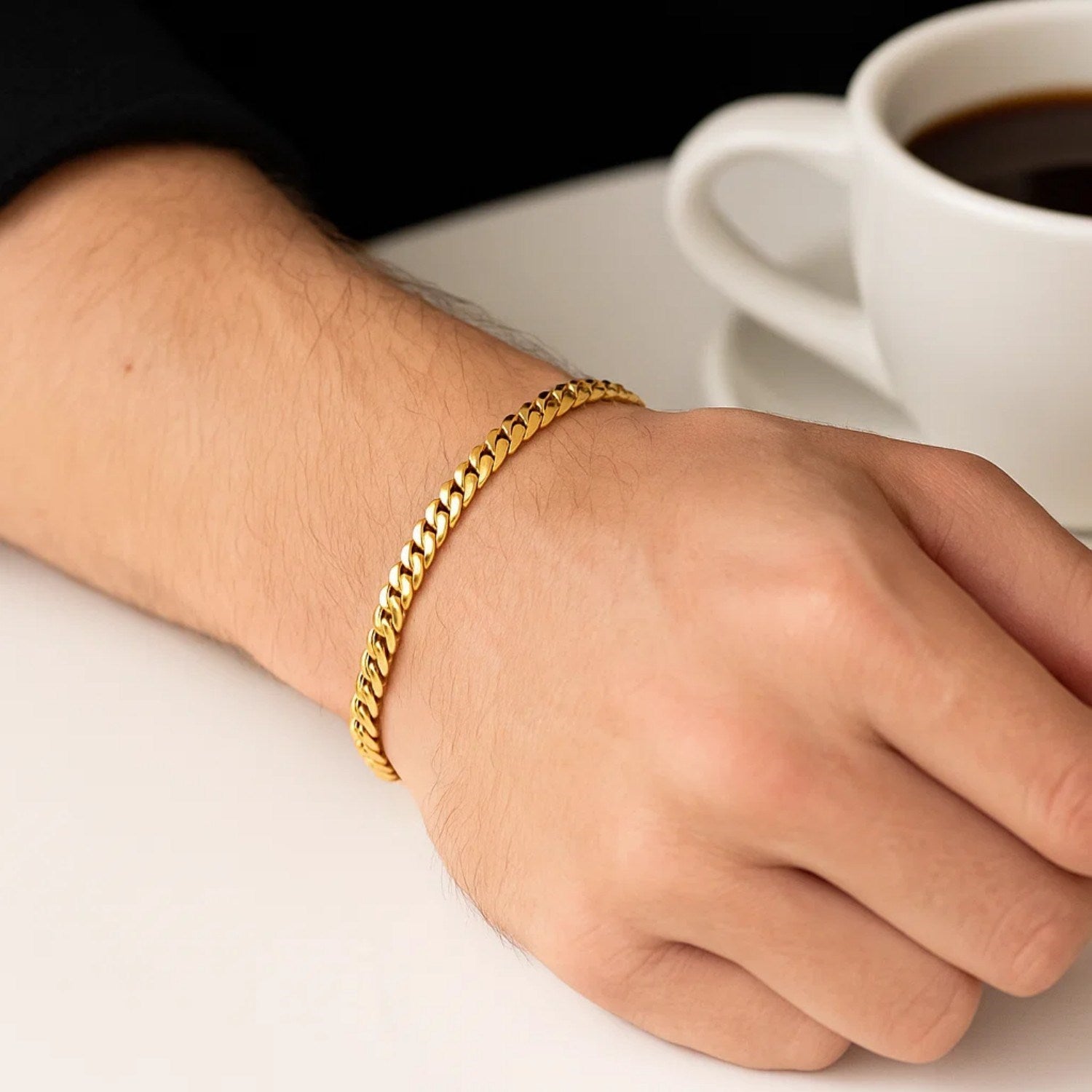 10k yellow gold Miami Cuban semi-solid bracelet on a person's wrist next to a coffee cup.