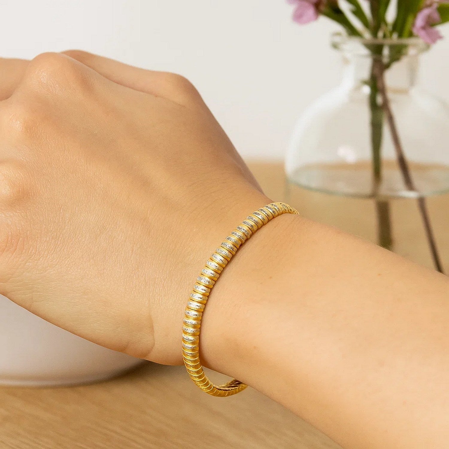 14k yellow gold flex bracelet with diamante accents on a person's wrist.