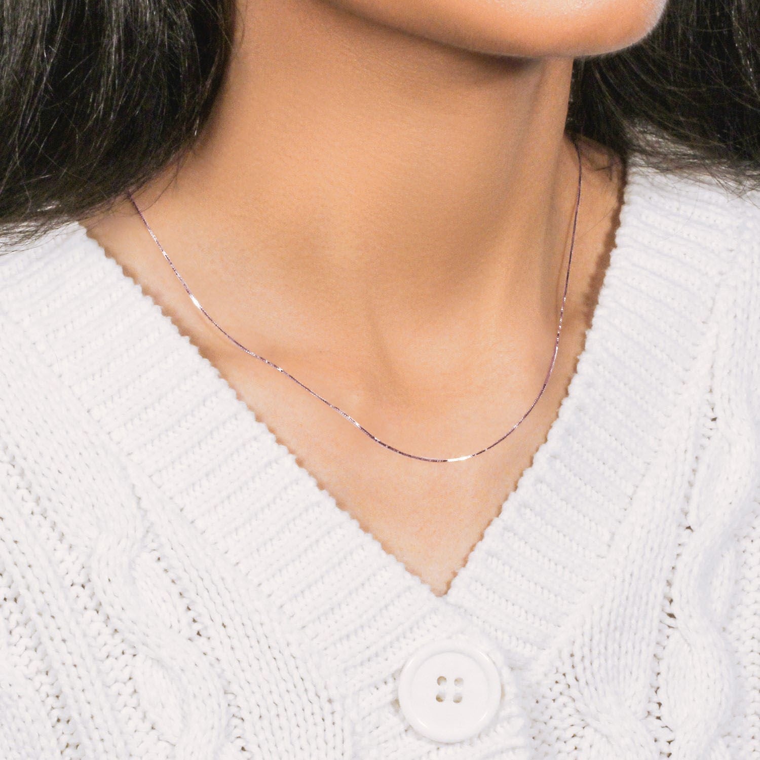 An 18k rose gold classic box chain is worn around a person's neck.