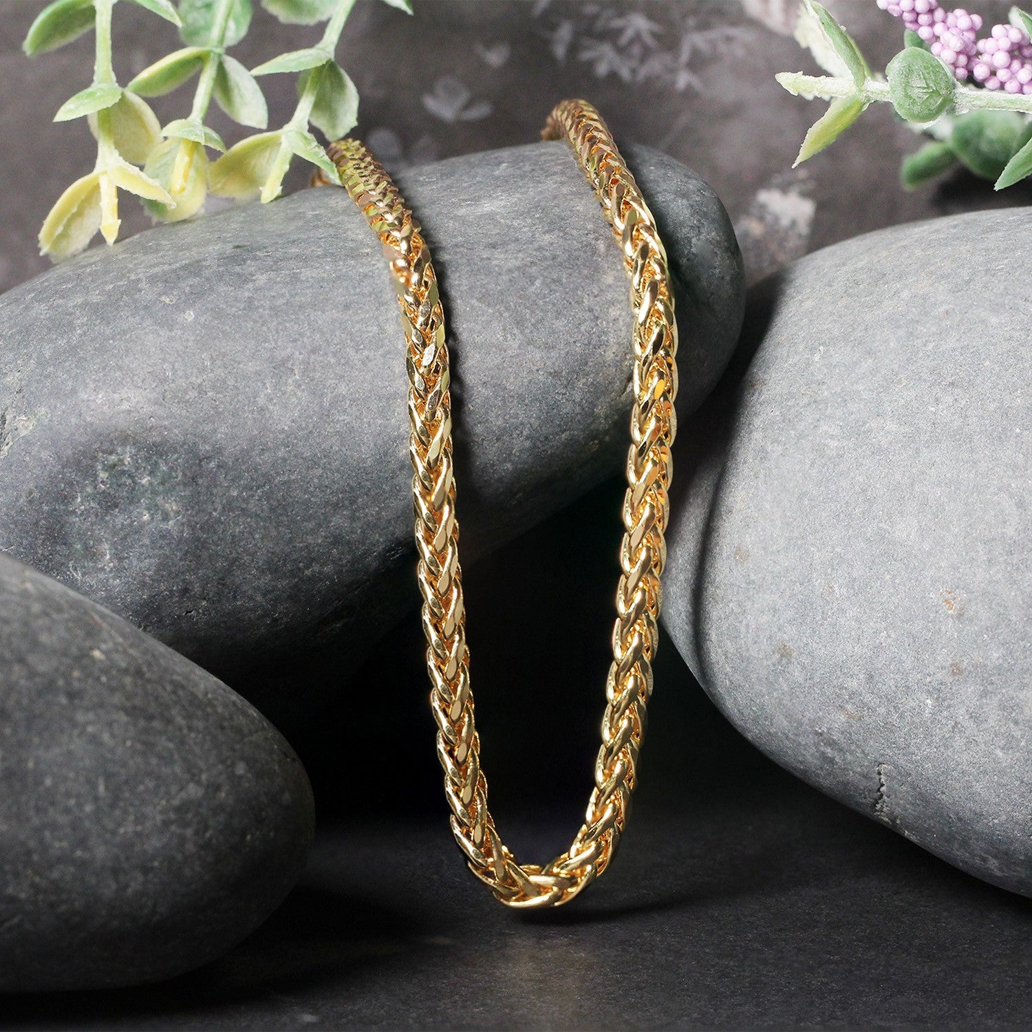 A 4.1mm 14k yellow gold diamond cut round Franco chain rests on grey stones.