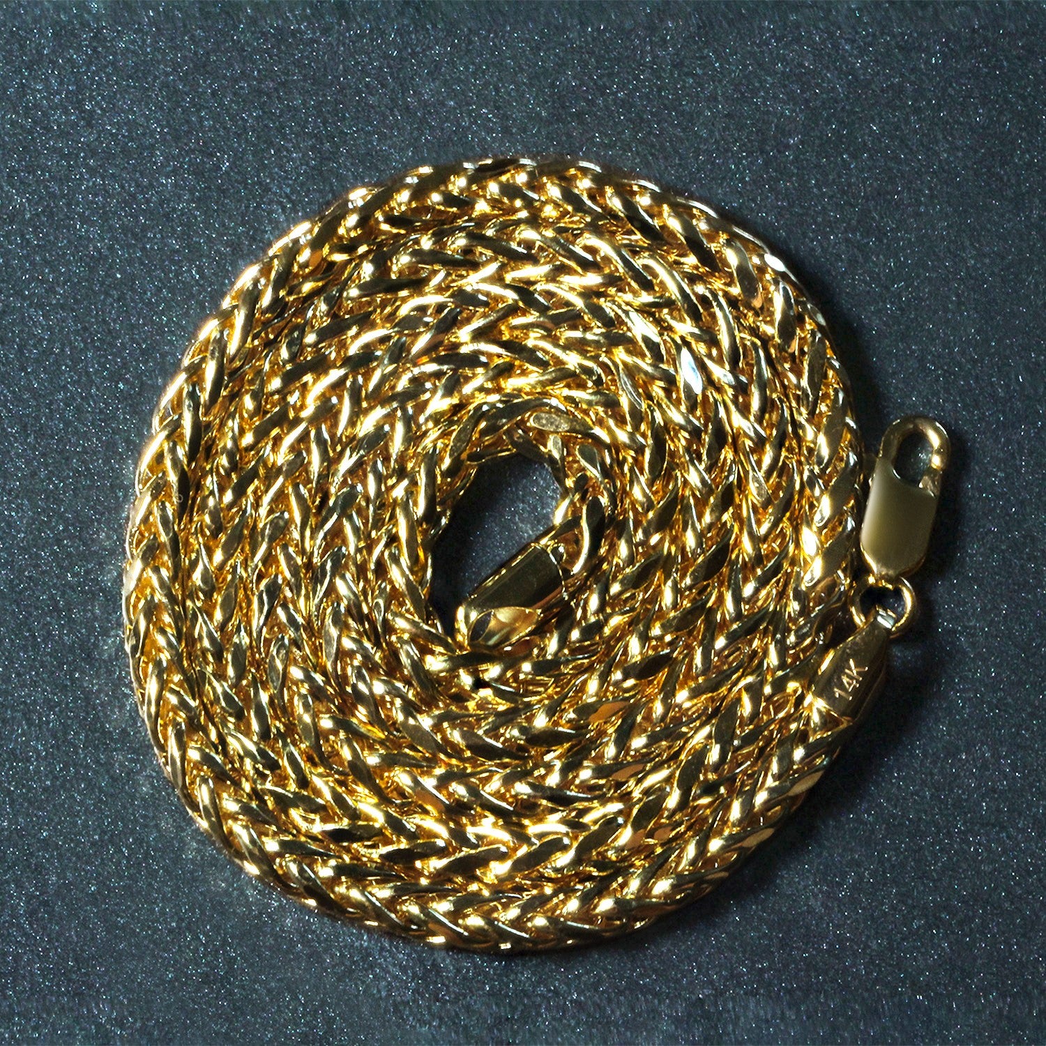 A coiled 14k yellow gold diamond cut round Franco chain with a lobster clasp.