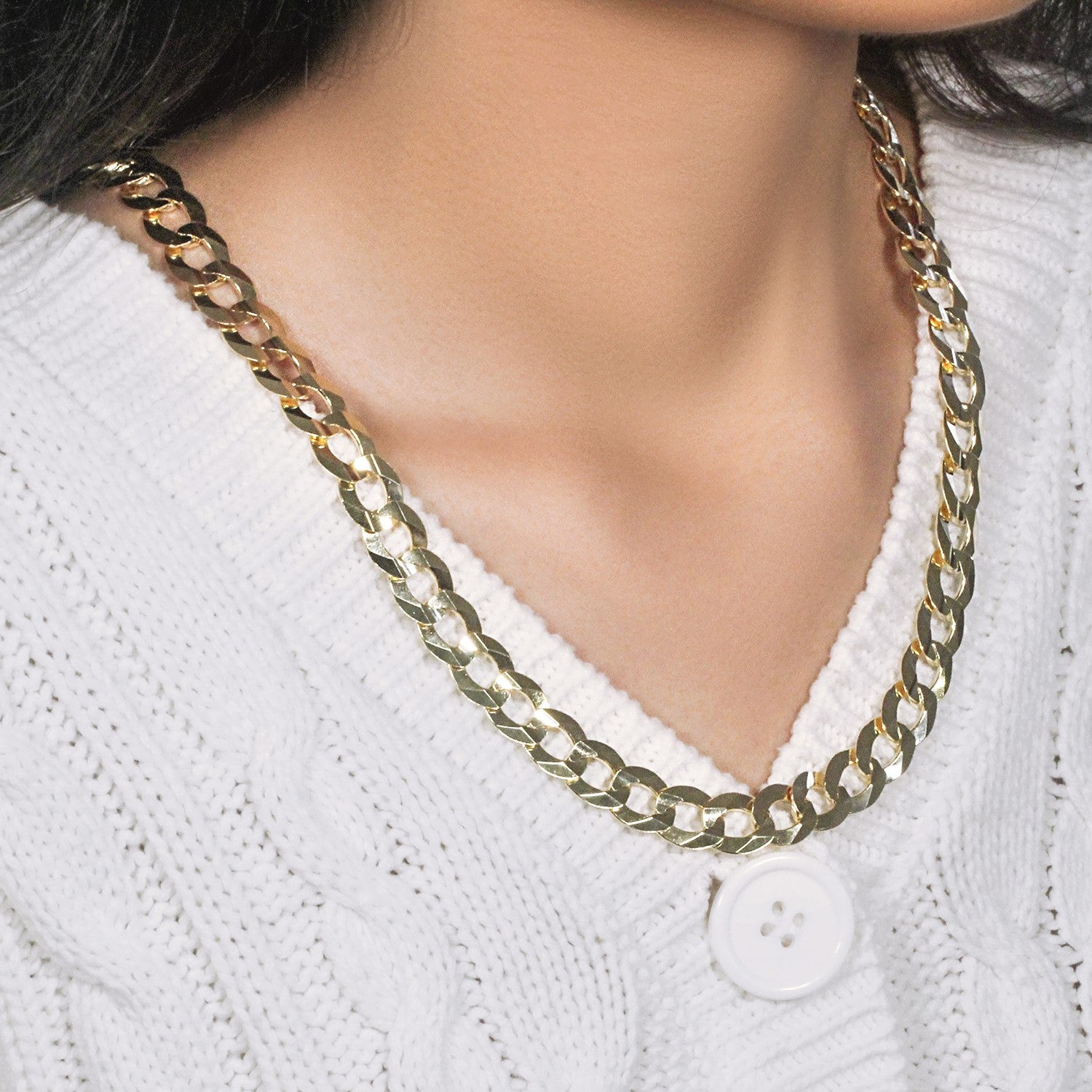 A solid 14k yellow gold curb chain on a person wearing a white sweater.