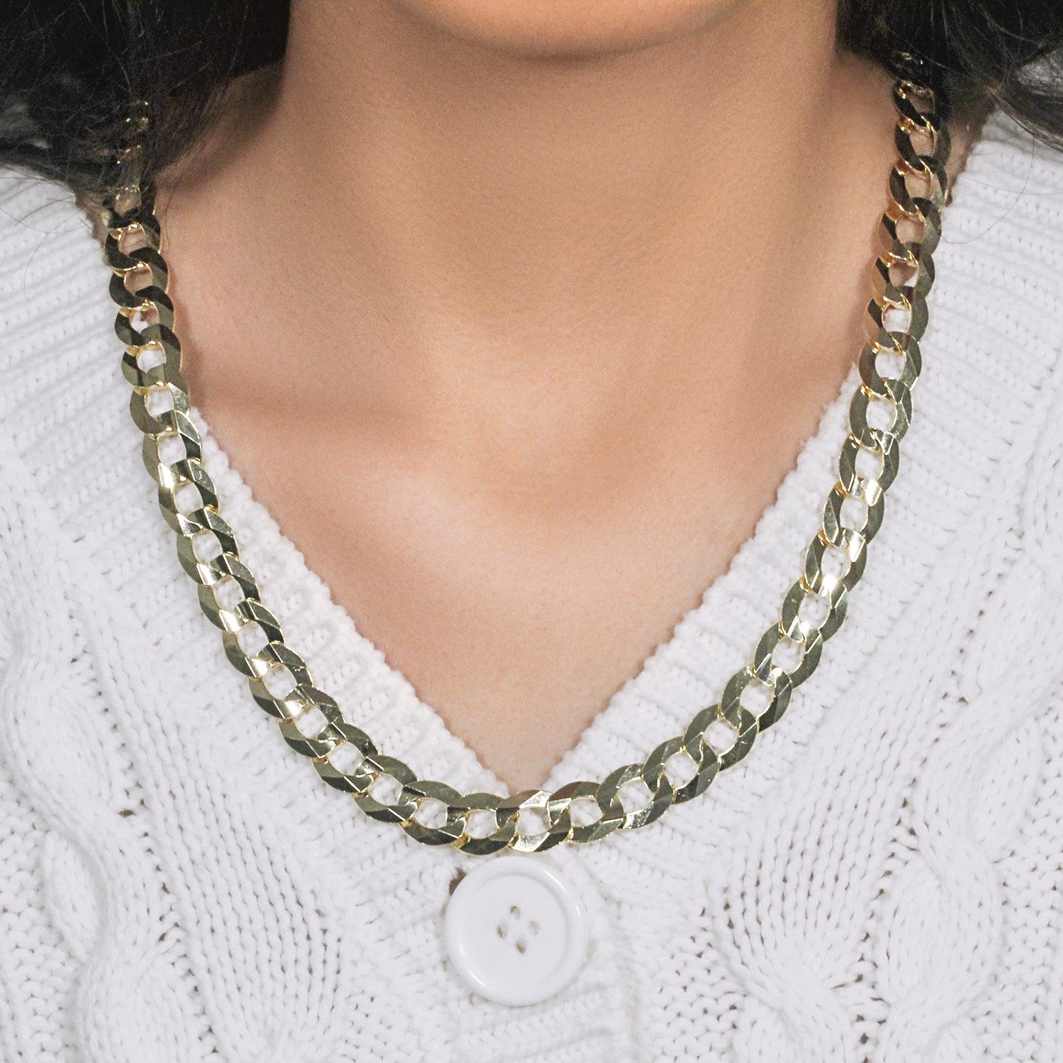 A solid 14k yellow gold curb chain necklace on a person wearing a white sweater.