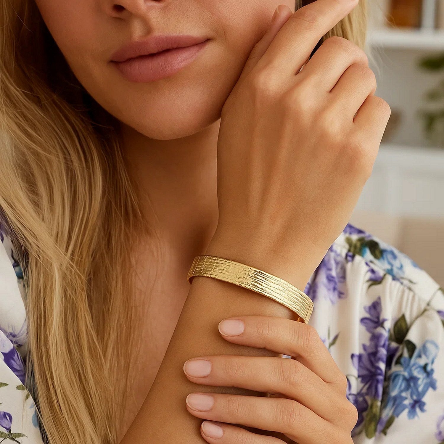 A woman wears a textured 14K yellow gold bracelet on her left wrist.