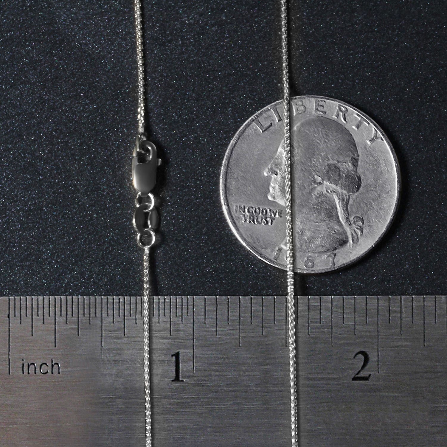 A 14k white gold round wheat chain with a lobster clasp, shown next to a ruler and coin.