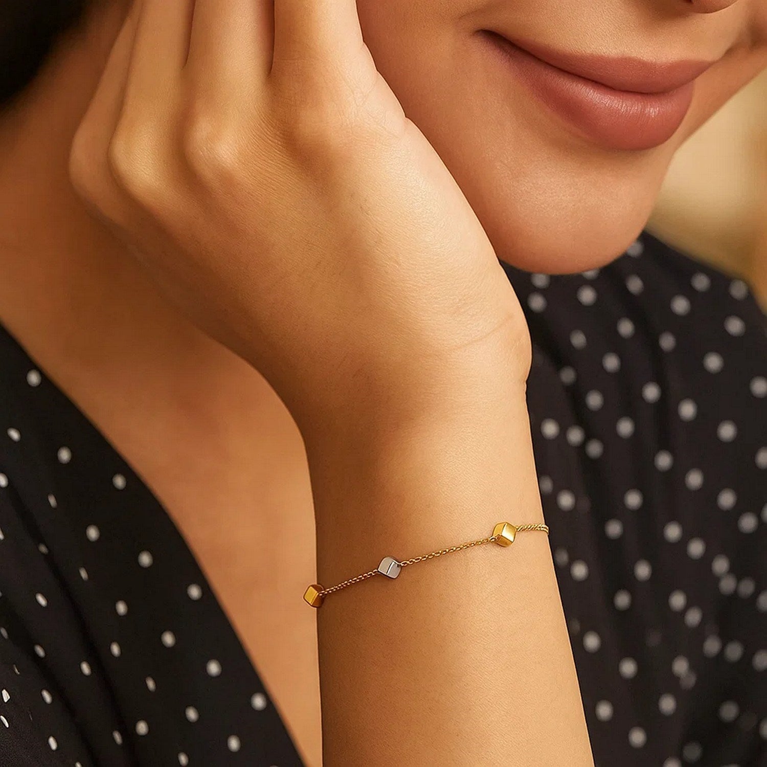 14k two-tone gold bracelet with polished yellow and white gold cubes on a woman's wrist.