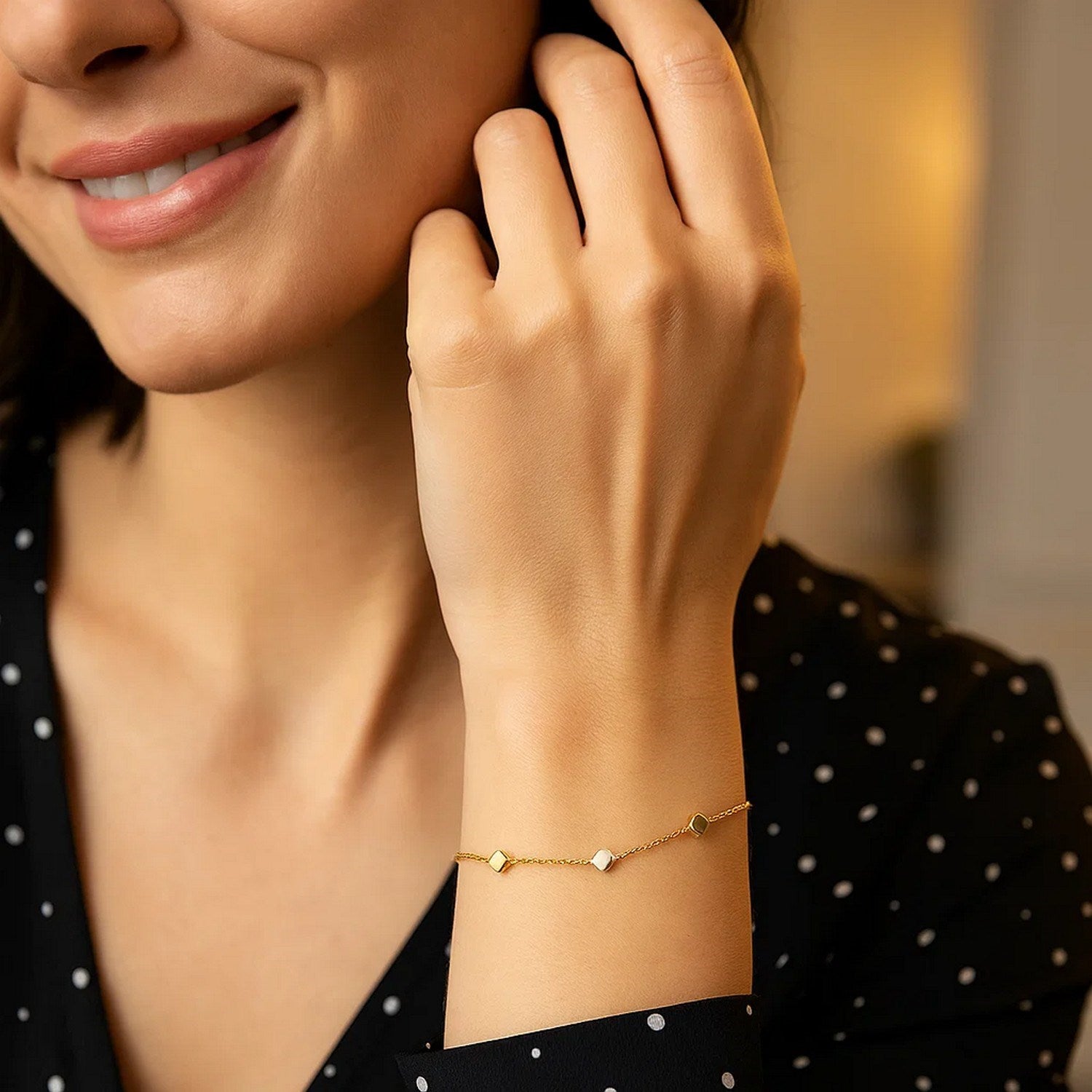 14k two-tone gold bracelet with polished yellow and white gold cubes on a woman's wrist.