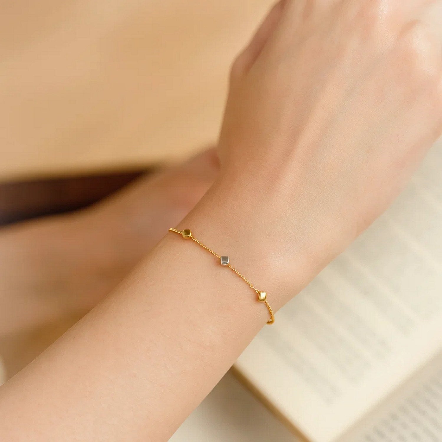 14k two-tone gold bracelet with polished yellow and white gold cubes on a wrist.