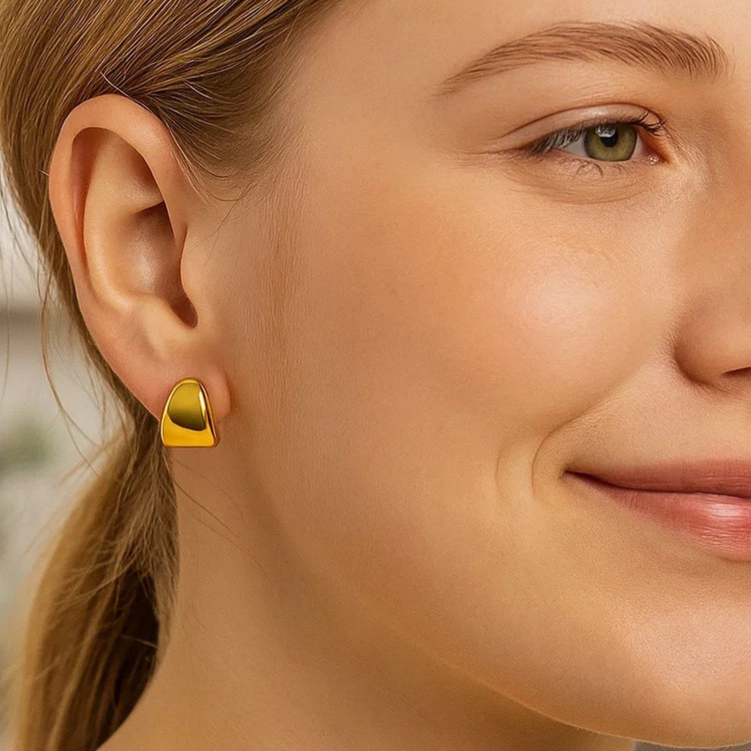 A woman models a single puffed up graduated hoop earring in 14K yellow gold.