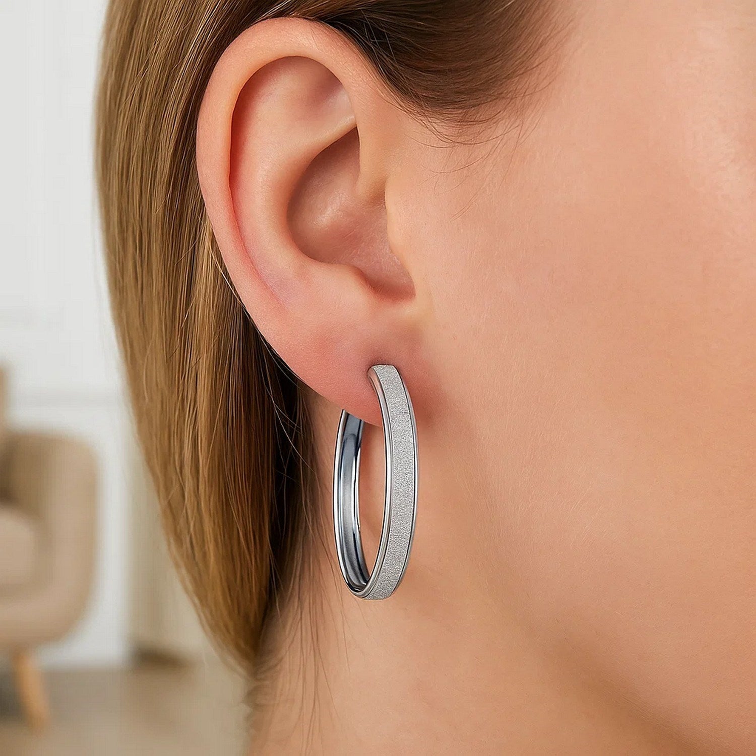A woman wears a single 14k white tone gold hoop earring with a glitter look design.