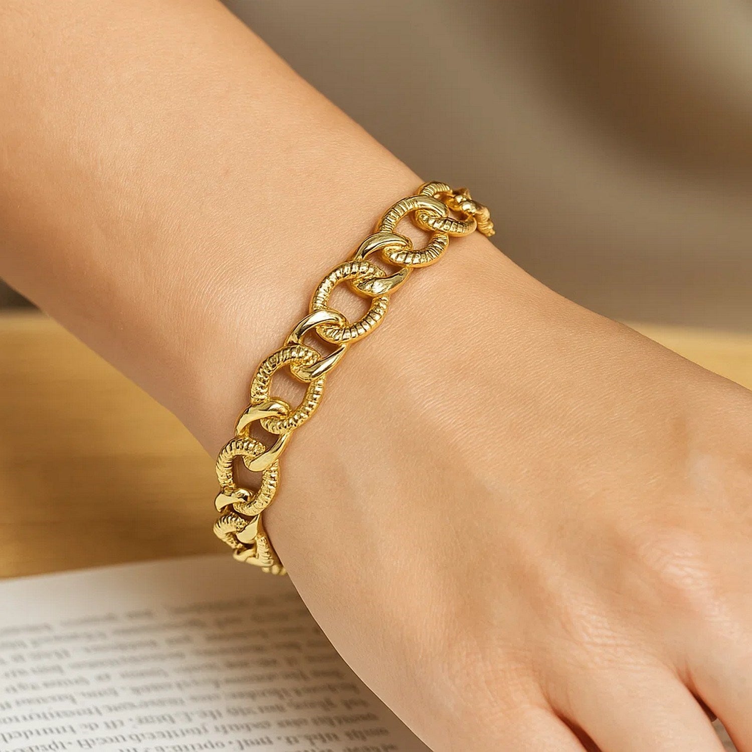 A 14k yellow gold curb chain bracelet with diamond cuts on a person's wrist.