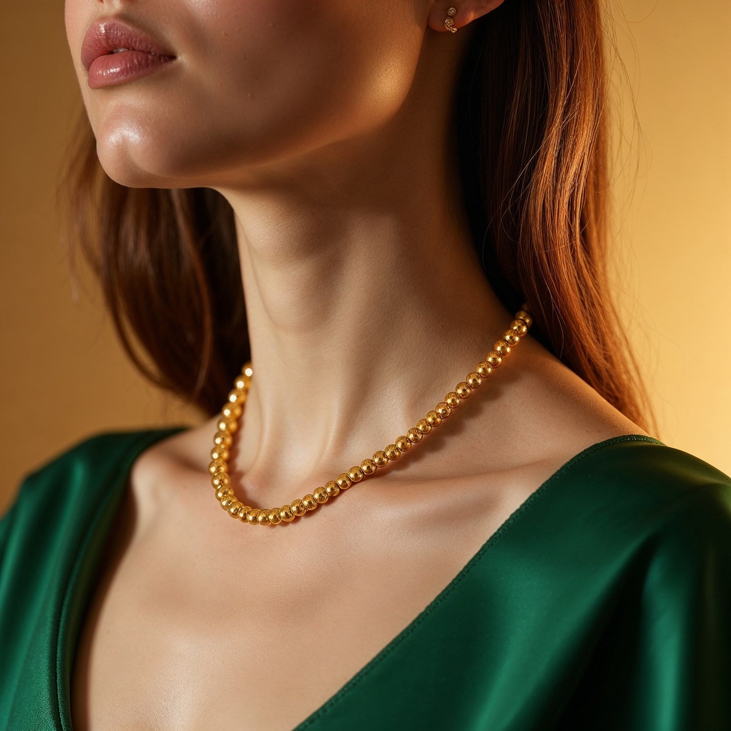 14k yellow gold bead chain on a woman wearing a green top.