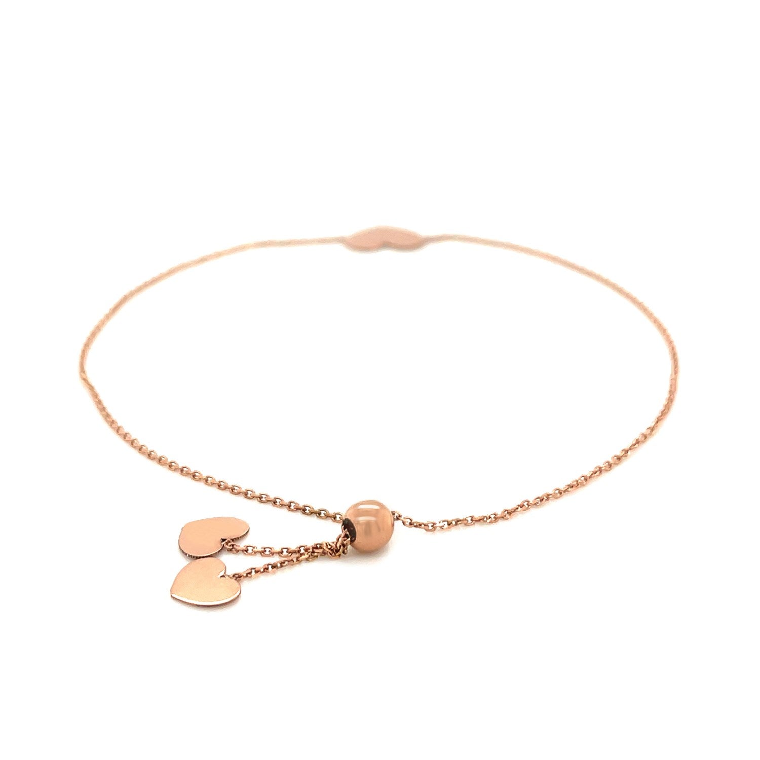 14k rose gold adjustable bracelet with two dangling hearts and a round bead.