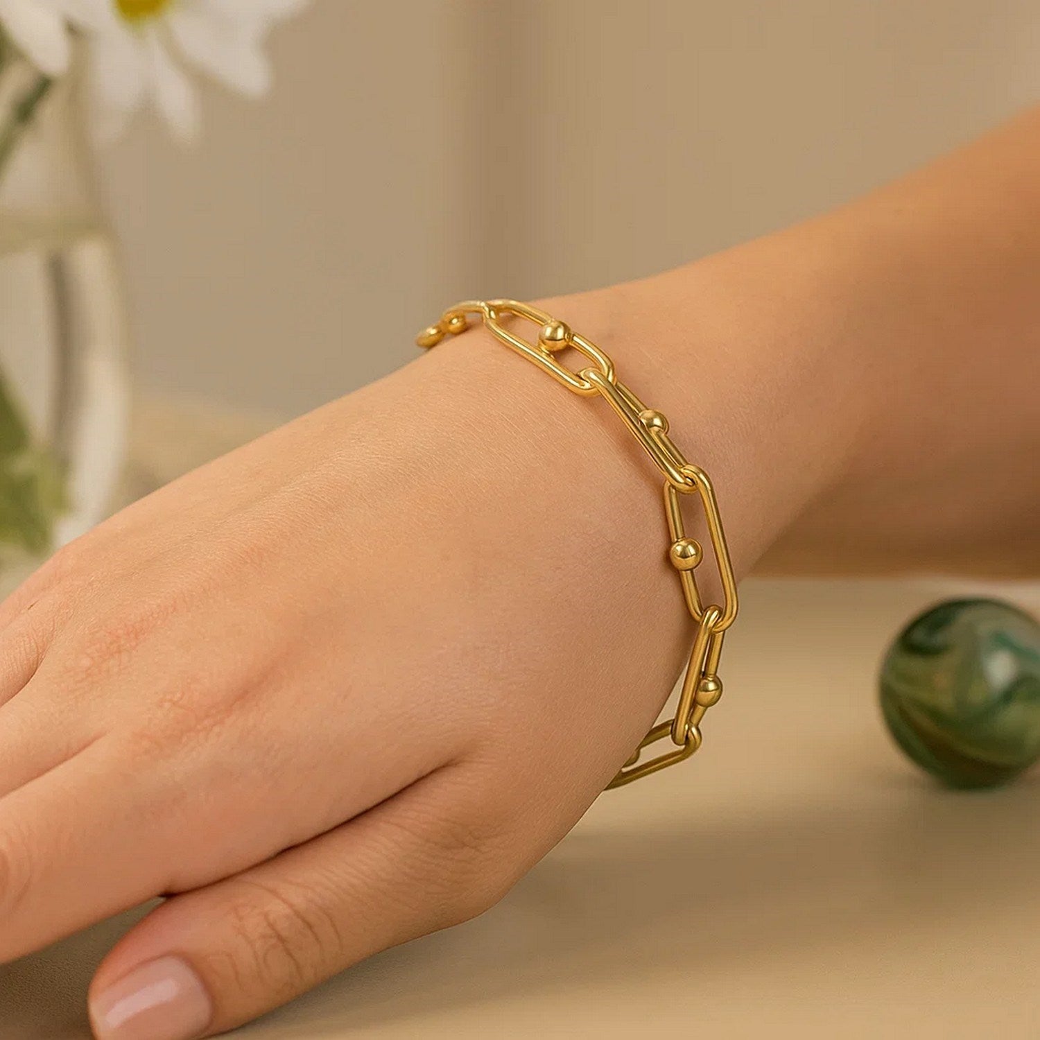 14k yellow gold beaded oval chain bracelet on a person's wrist.