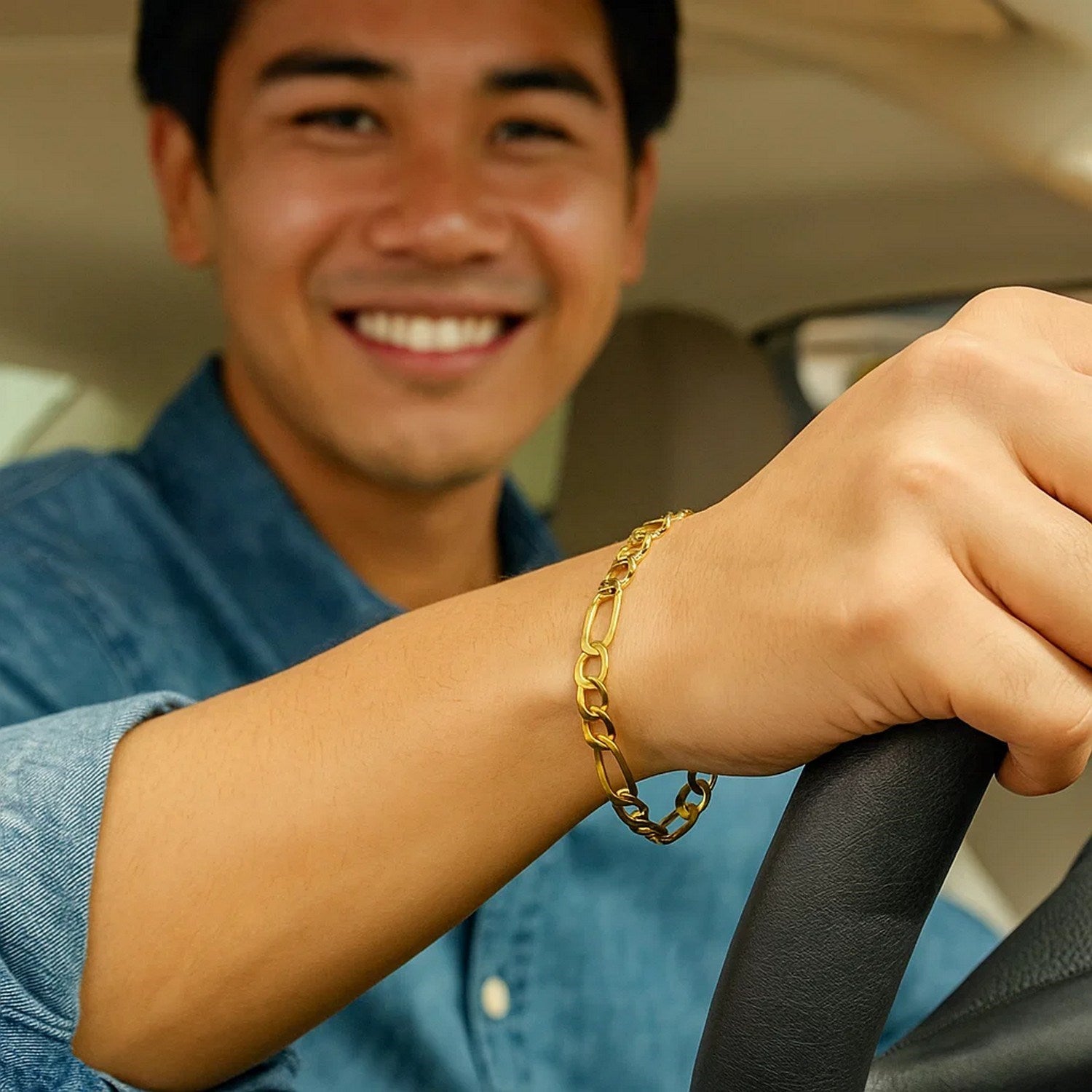 10k yellow gold lite Figaro bracelet on a person's wrist while driving.