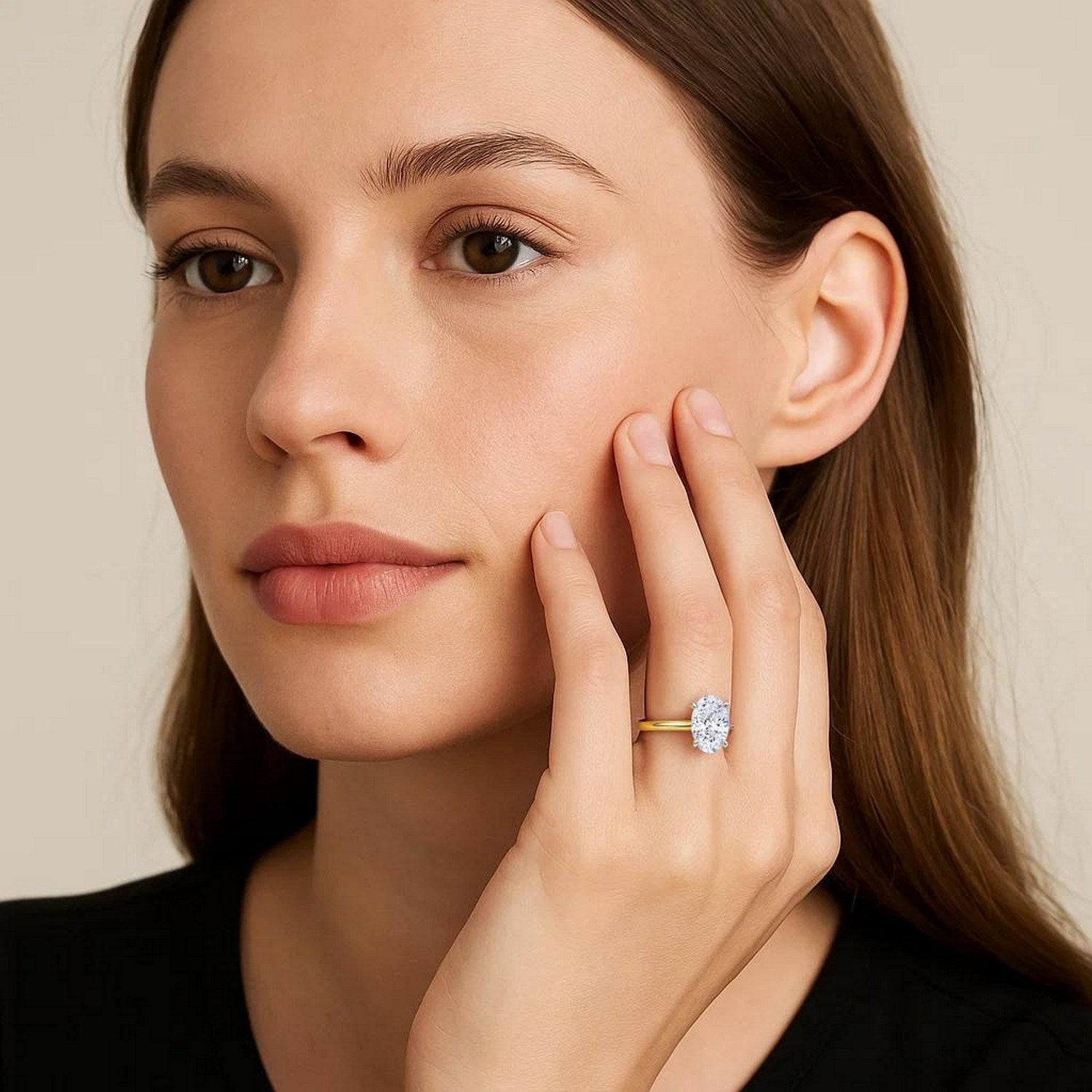 A woman wears an oval lab-grown diamond solitaire ring on a yellow gold band.