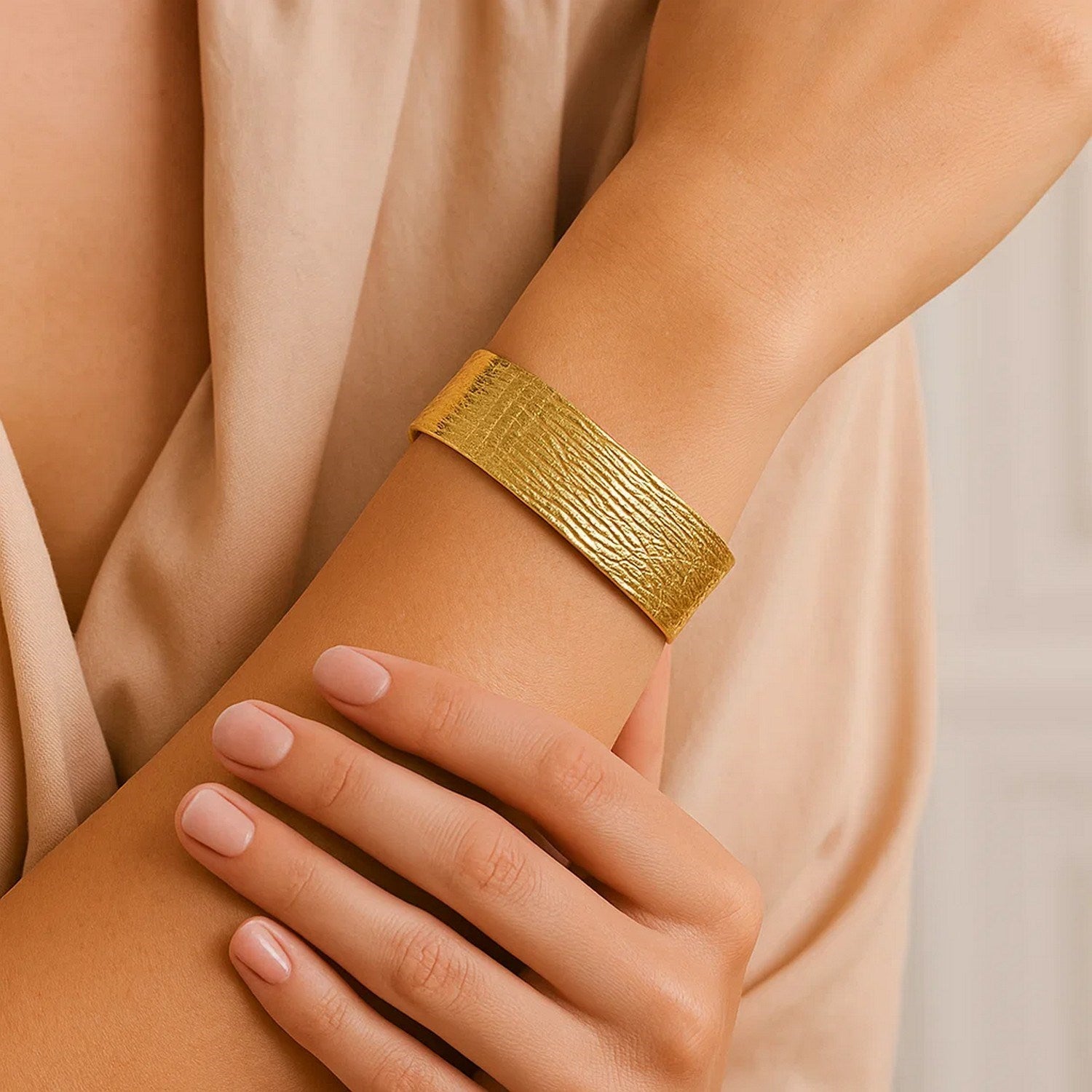 14K yellow gold bracelet with a textured, wide band on a person's arm.