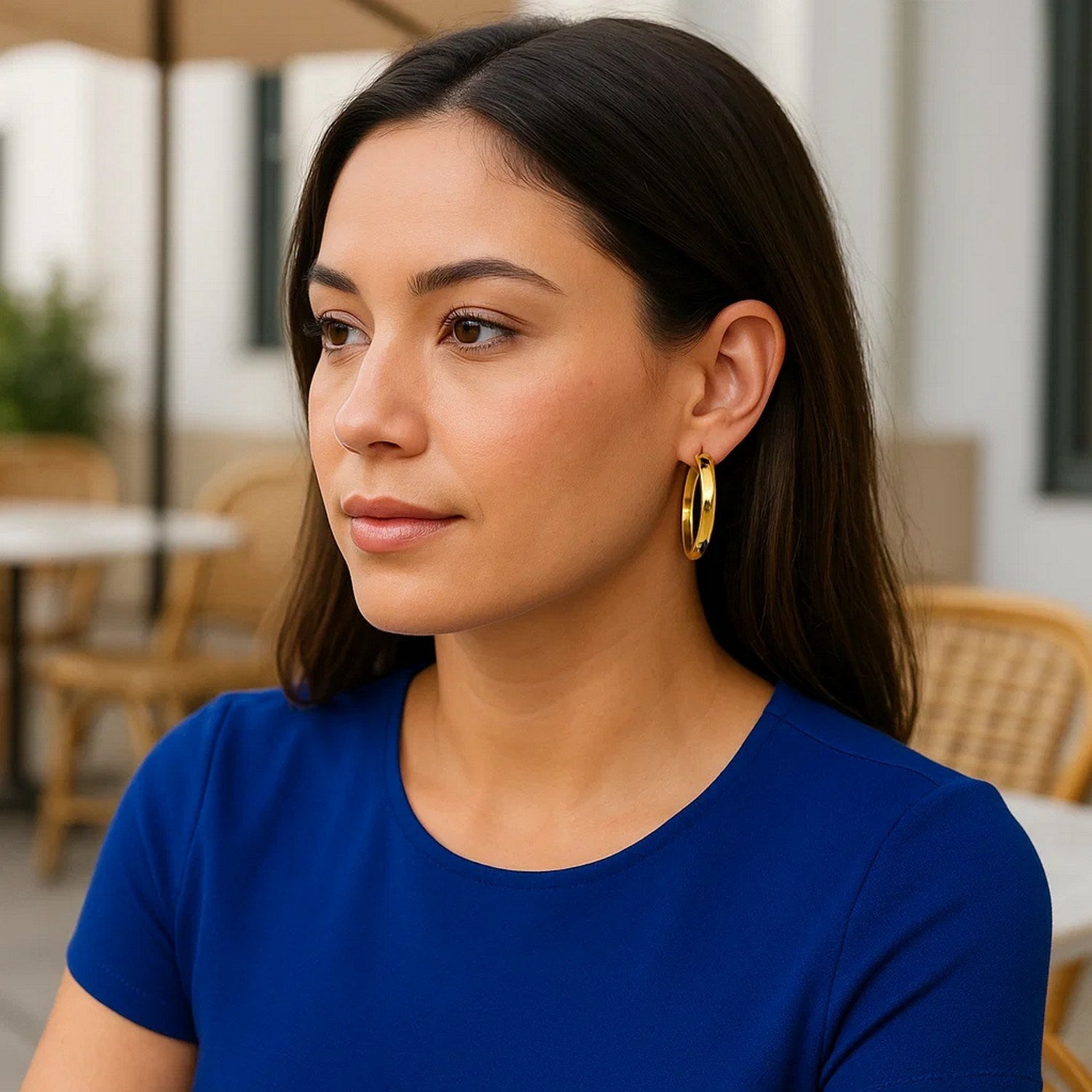 14k yellow gold wedding band hoops on a woman wearing a blue top.