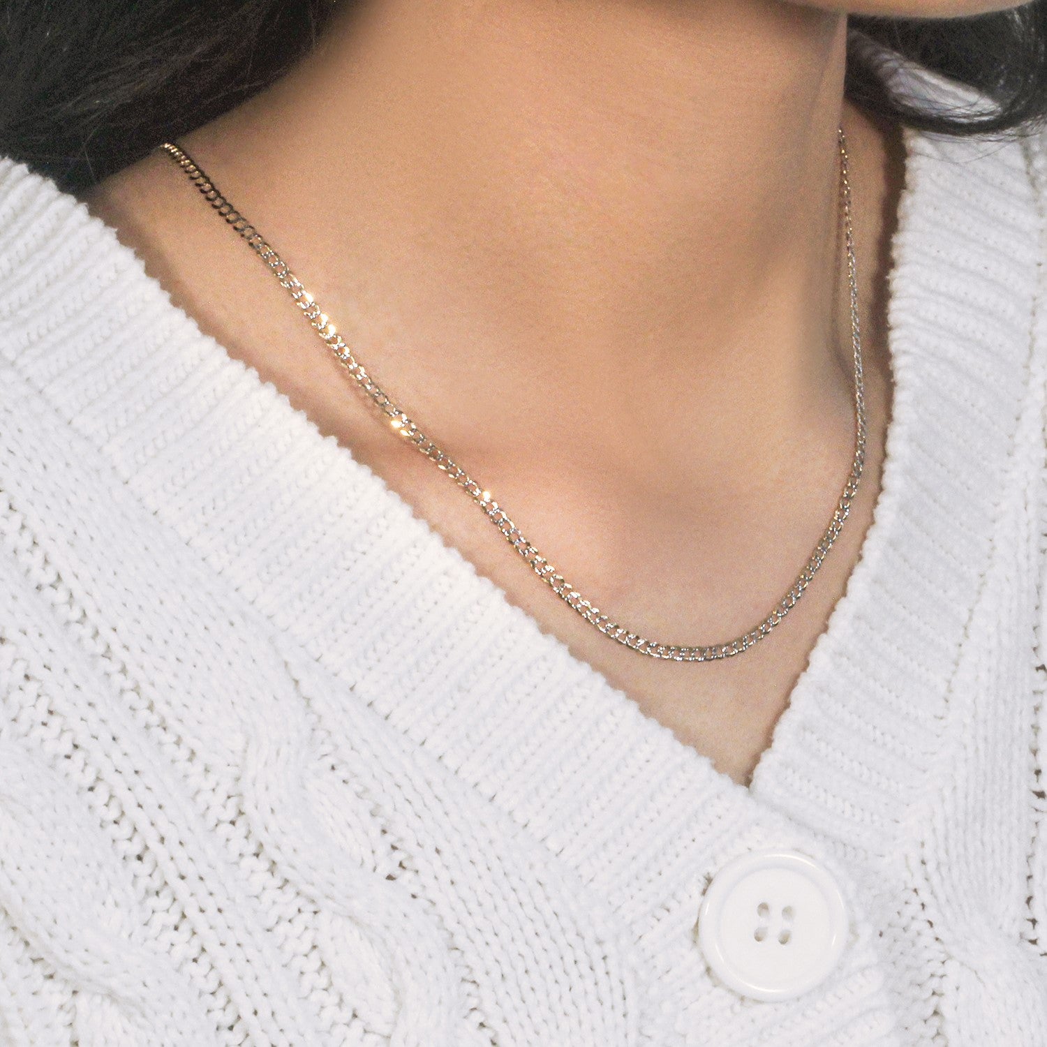 14k two-tone gold pave curb chain on a person wearing a white cable-knit sweater.