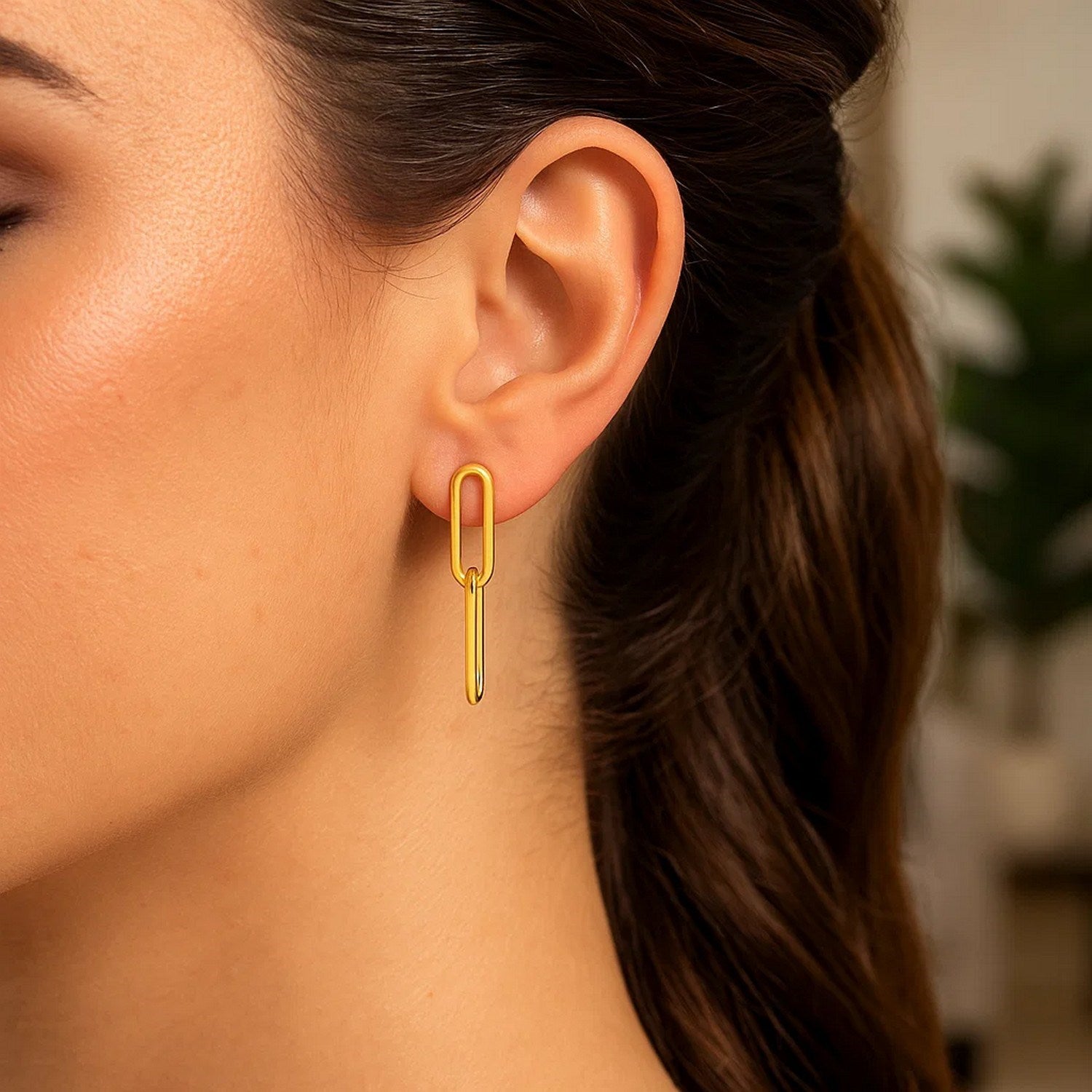 14K yellow gold two-link paperclip chain earrings on a woman's ear.