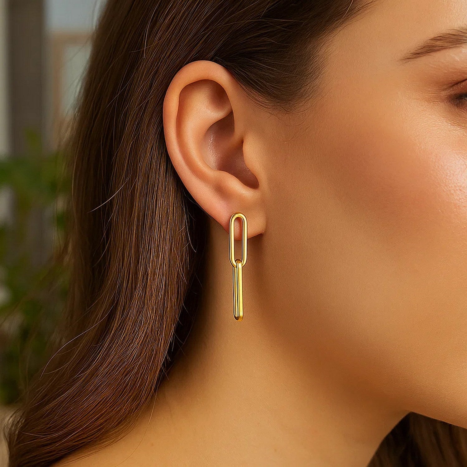 14K yellow gold two-link paperclip chain earrings on a woman's ear.